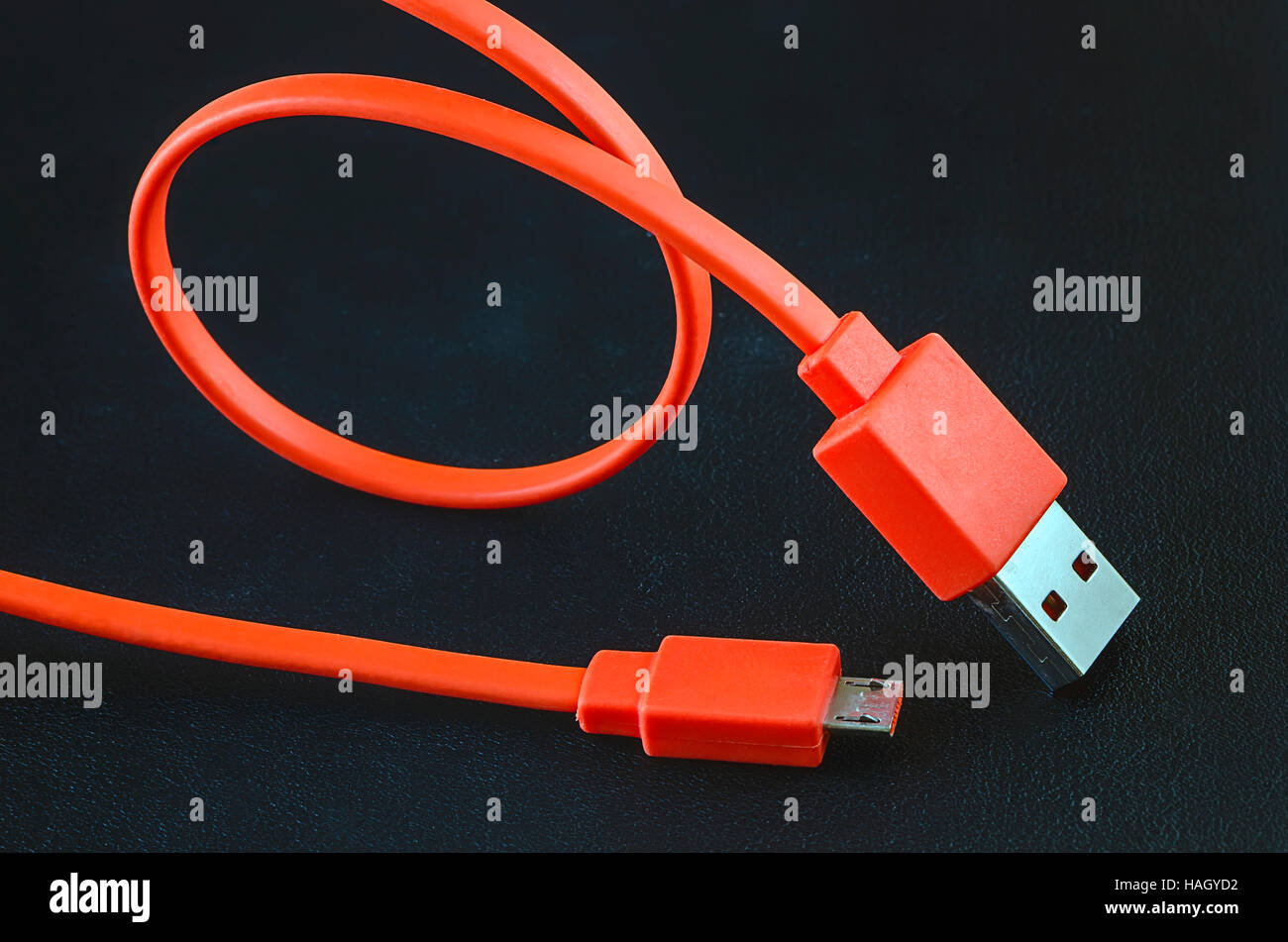Orange Farbe USB-Kabel auf schwarzem Leder Hintergrund. Stockfoto