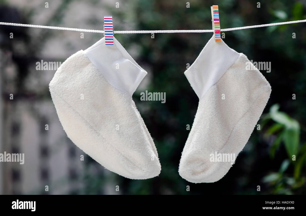Weiße Socken hängen an einem Seil mit bunten Wäscheklammer. Stockfoto