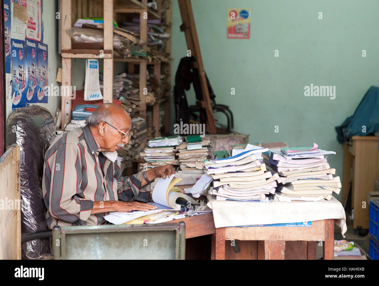 Älterer Mann sitzt an einem Schreibtisch seinen Papierkram, Indien zu tun. Stockfoto