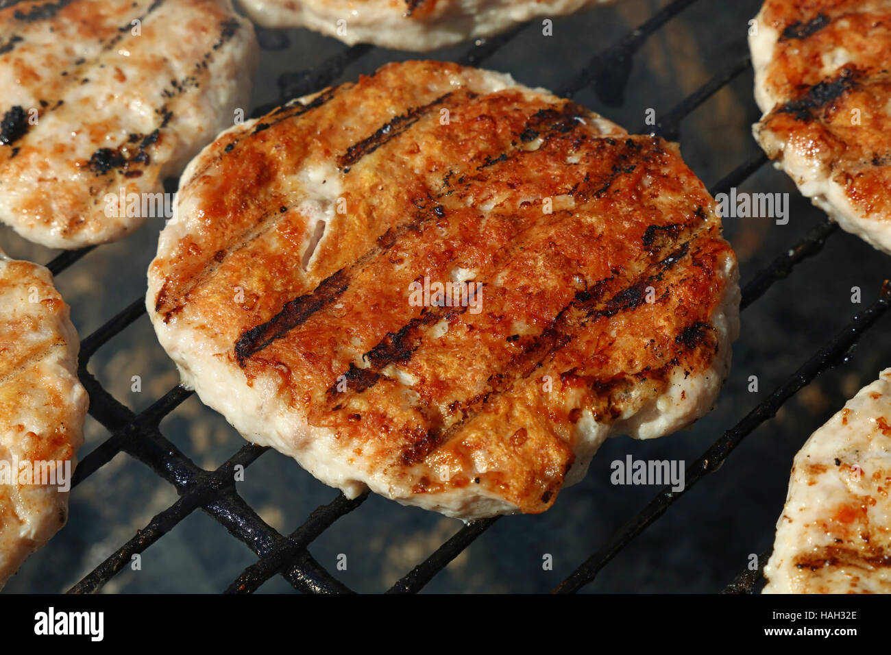 Ein Huhn oder Truthahn Geflügel Fleisch Grill gegrillte Burger für Hamburger vorbereitet auf Rauch Barbeque-Grill, Nahaufnahme Stockfoto