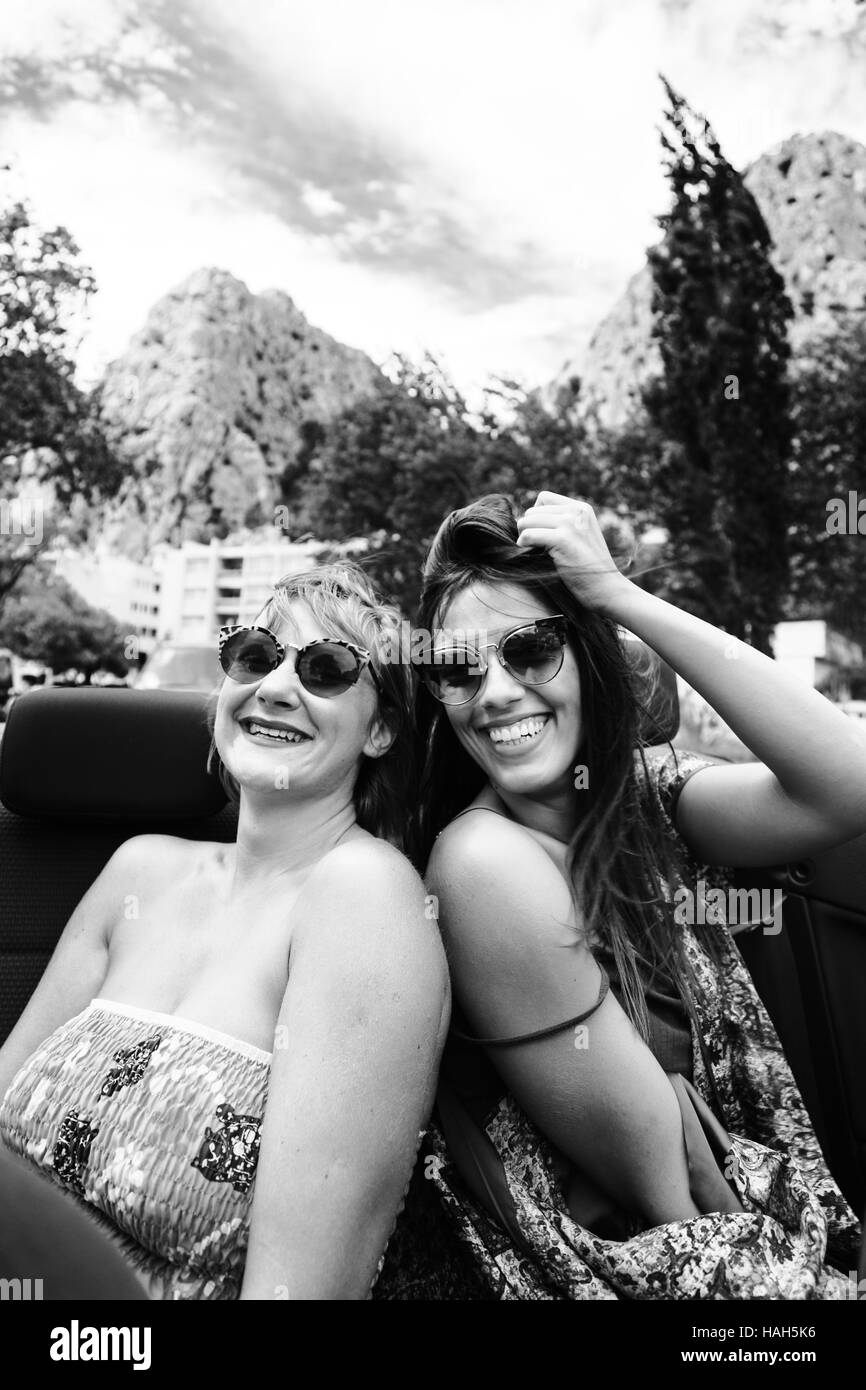 Zwei Mädchen, die Spaß auf dem Rücksitz des Cabrio. Schwarz / weiß-Filter angewendet. Stockfoto