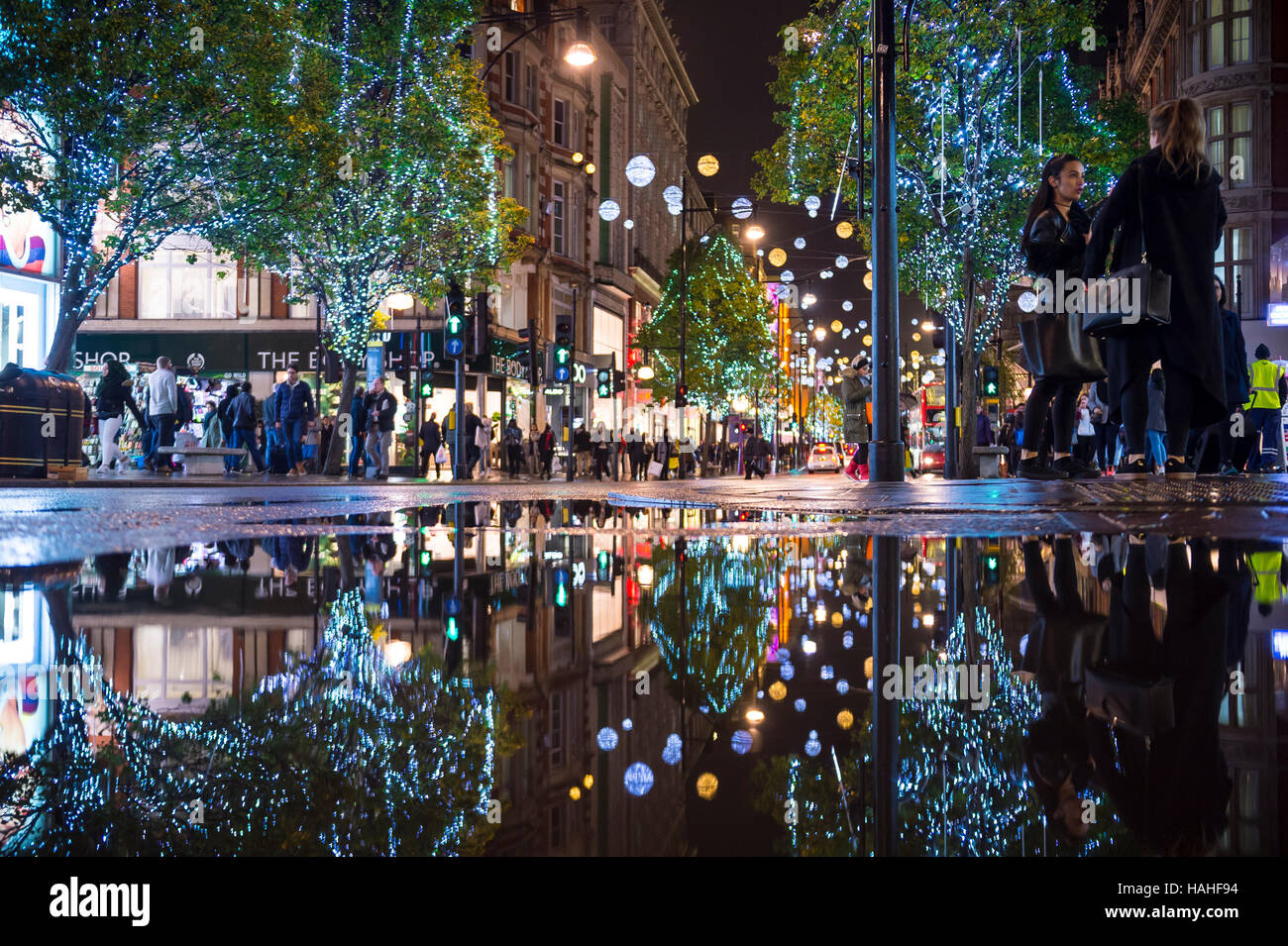 LONDON - 16. November 2016: Urlaub Lichter in einer Pfütze Reflexion Funkeln als Fußgänger drängen sich die Bürgersteige der Oxford Street. Stockfoto