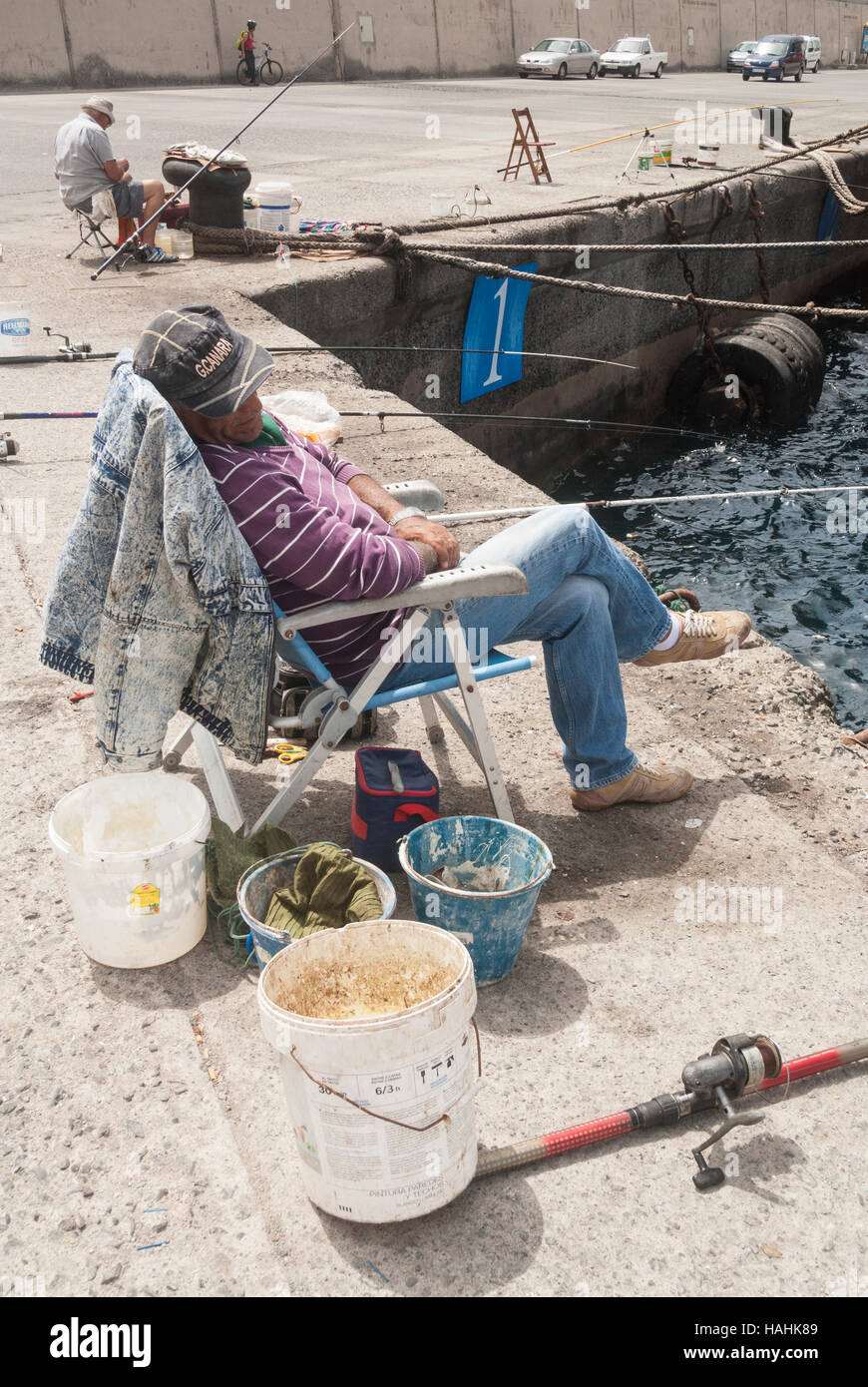 Spanischer Mann schlafen im Stuhl während des Fischens von Hafenmauer. Stockfoto