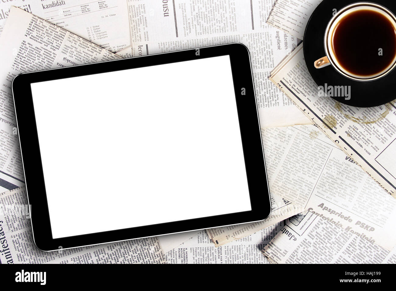 Digital-Tablette und Kaffeetasse auf Zeitungen Stockfoto