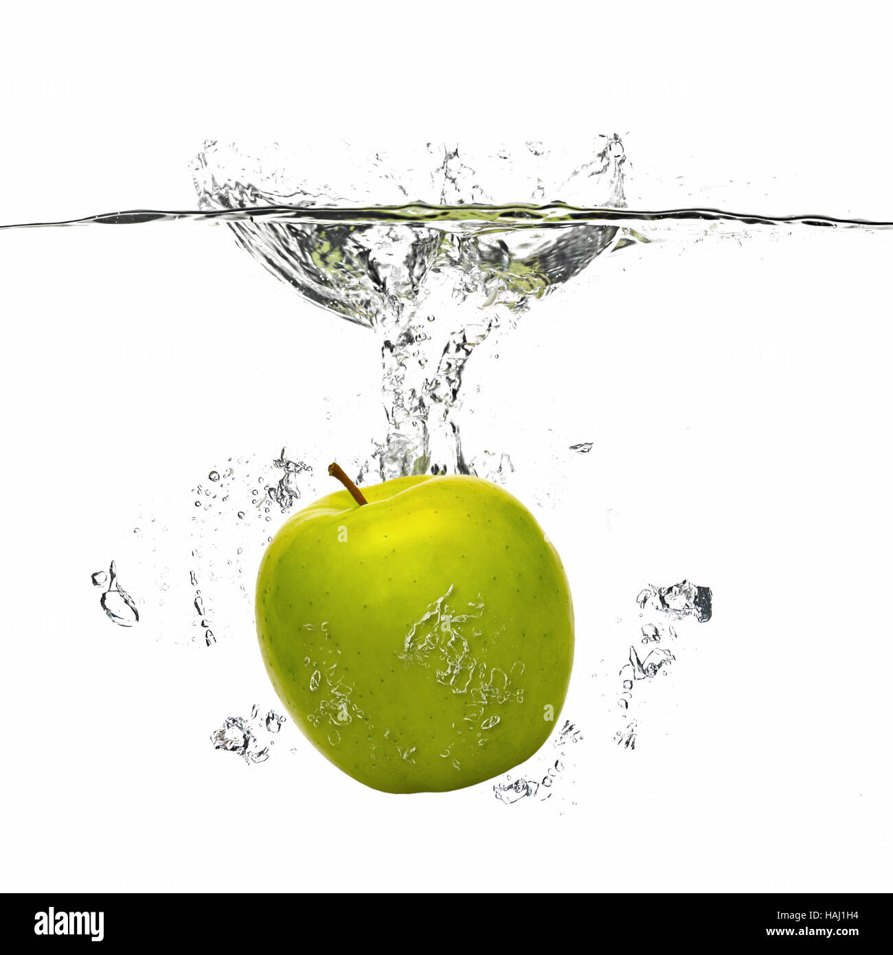 Apfel fällt ins Wasser mit Spritzen auf weiß Stockfoto