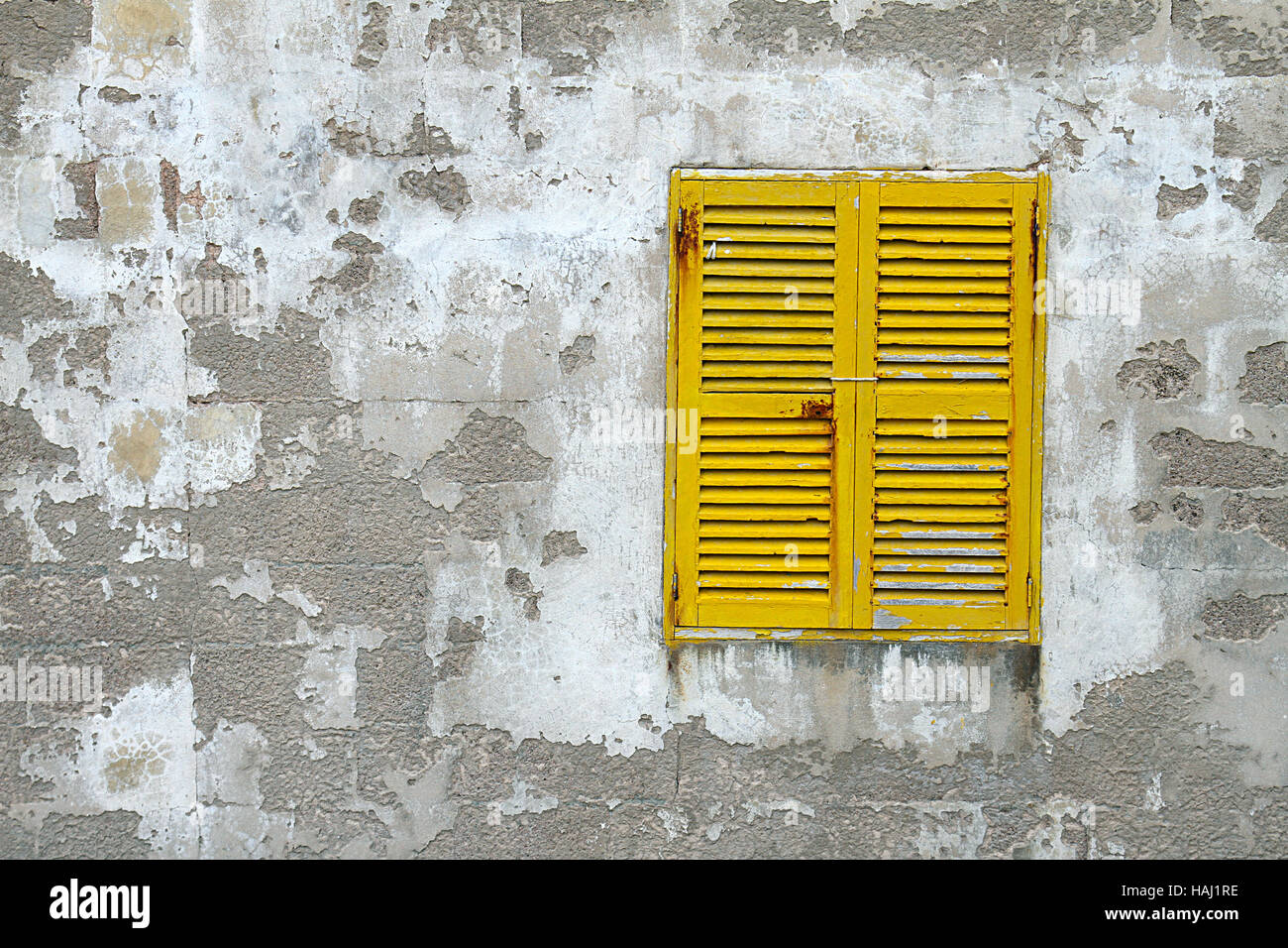 gelben hölzernen Fensterläden auf der alten Steinmauer geschlossen Stockfoto