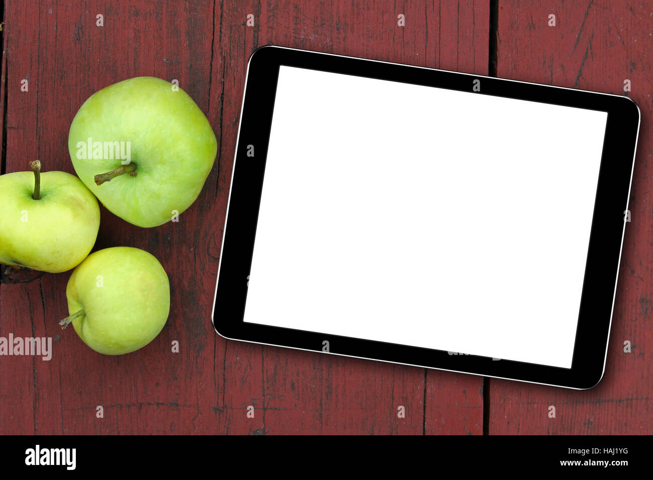 leere Tablet und Äpfel auf dem roten Holztisch Stockfoto