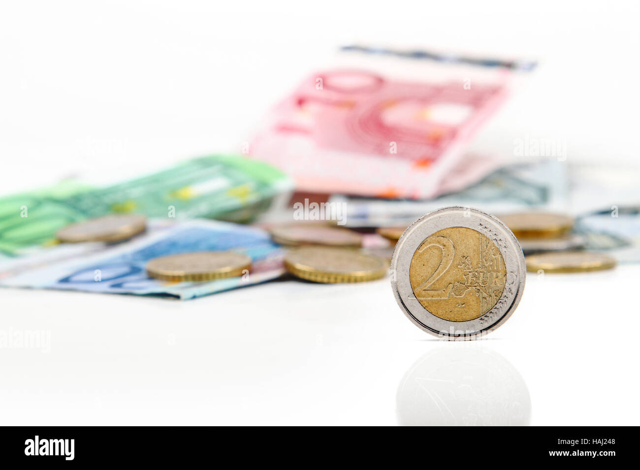 zwei-Euro-Münze mit anderen Euro-Münzen und Banknoten im Hintergrund Stockfoto