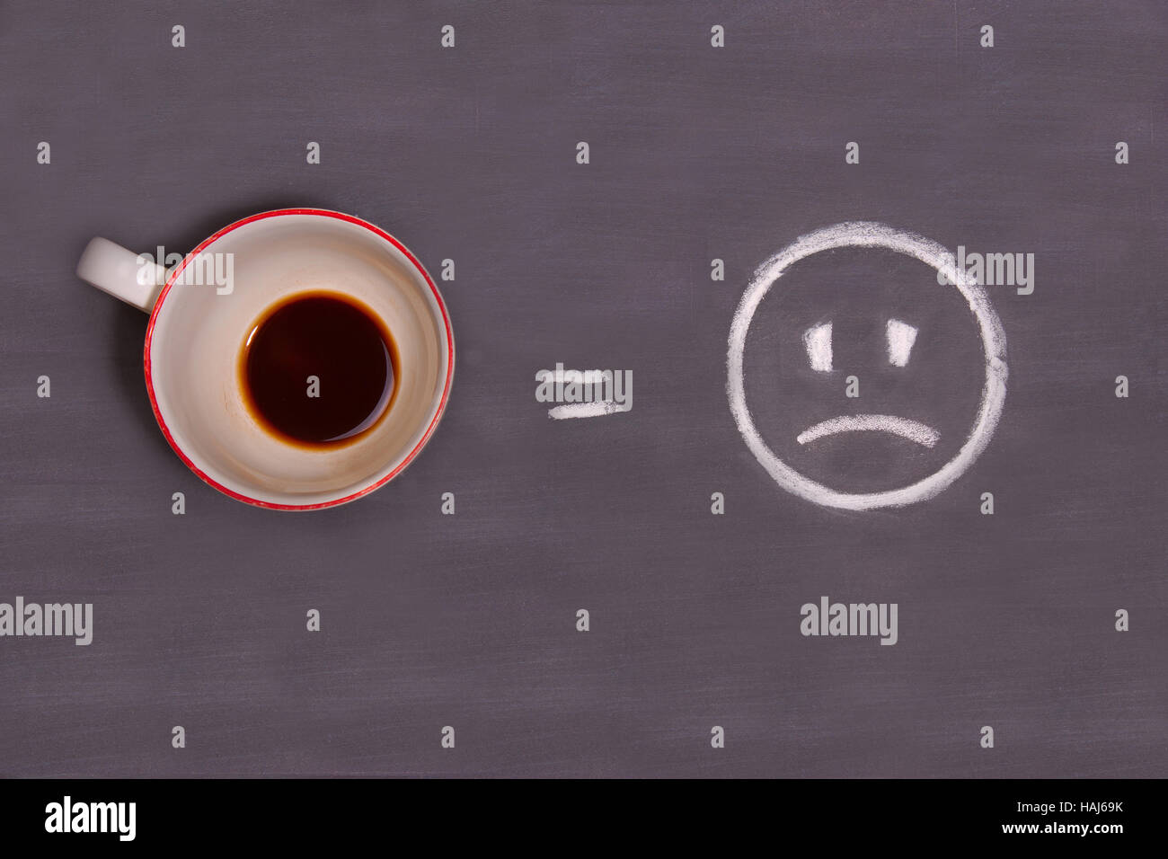 Eine Tasse Kaffee und traurige Smiley mit Kreide auf den Tisch gezogen. Energie aus dem Kaffee. Stockfoto