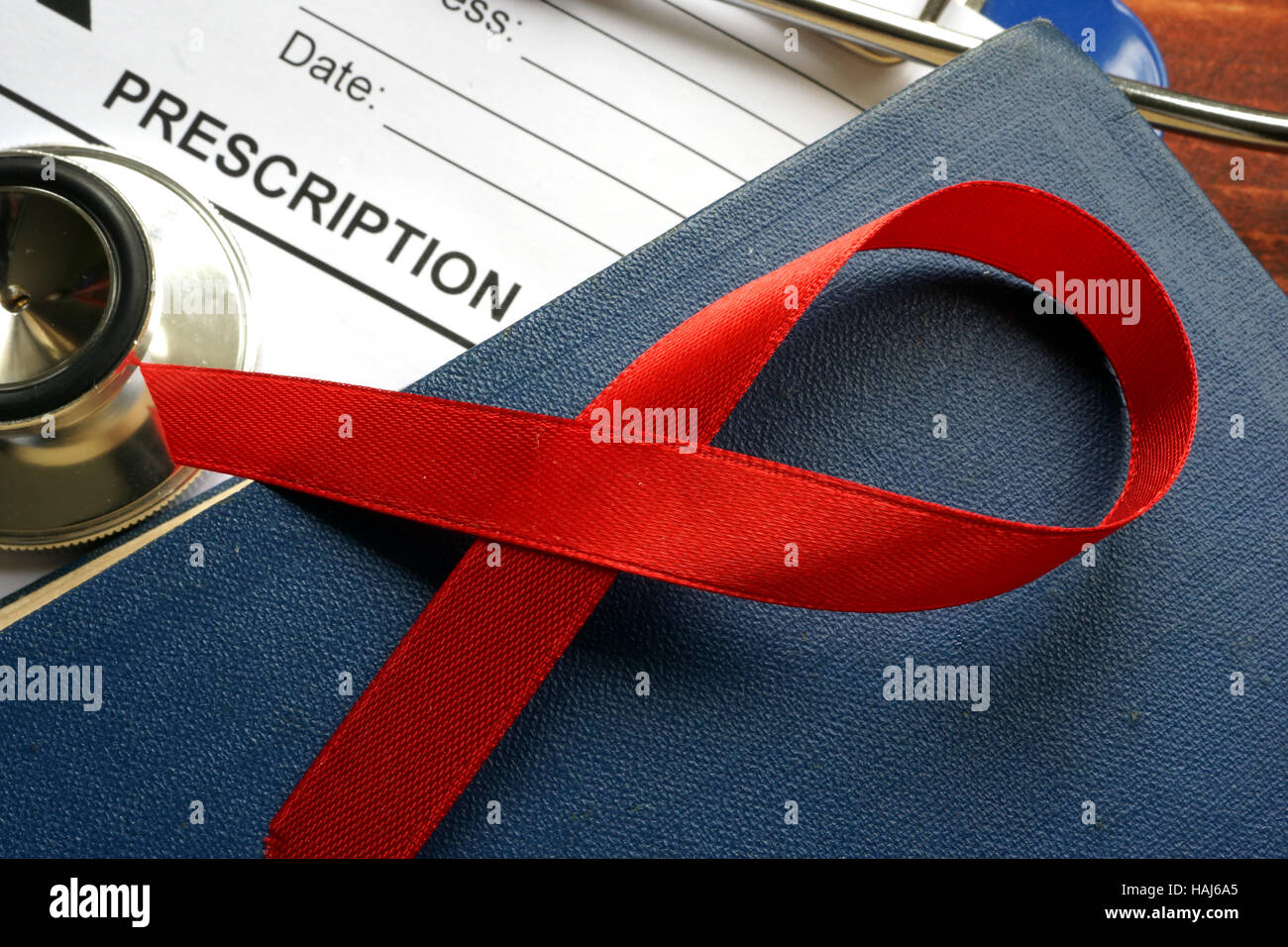 HIV/AIDS-Konzept. Rote Schleife an einem Buch. Stockfoto