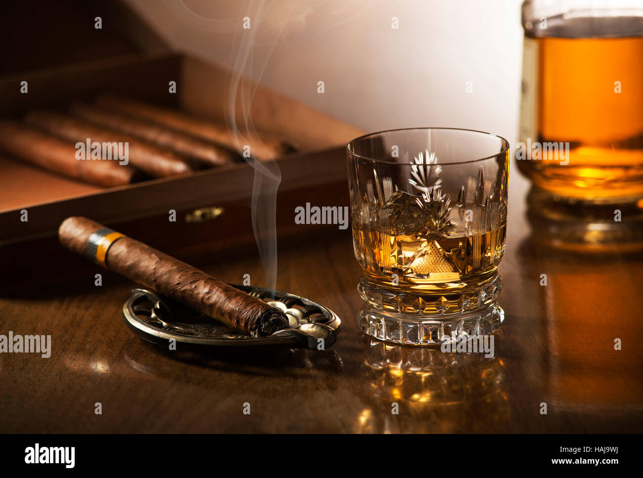 Glas Whiskey mit Eiswürfeln und rauchende Zigarre auf Holztisch Stockfoto