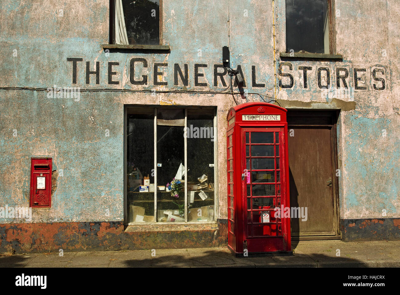Rote Telefondose und Briefkasten vor dem stillstehenden Geschäft, Mathry, Pembrokeshire, Wales, Großbritannien. Stockfoto