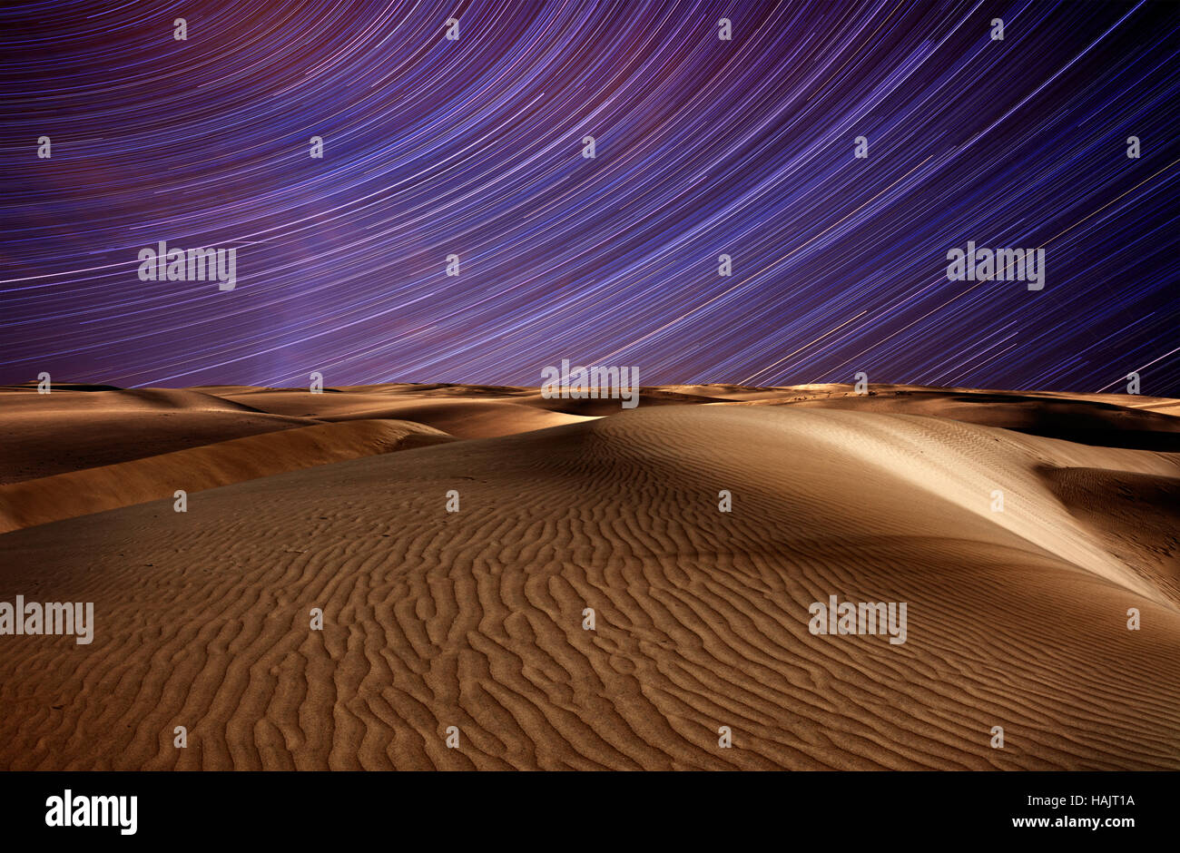 Nacht in der Wüste Sanddünen und Sternspuren am blauen Nachthimmel Stockfoto