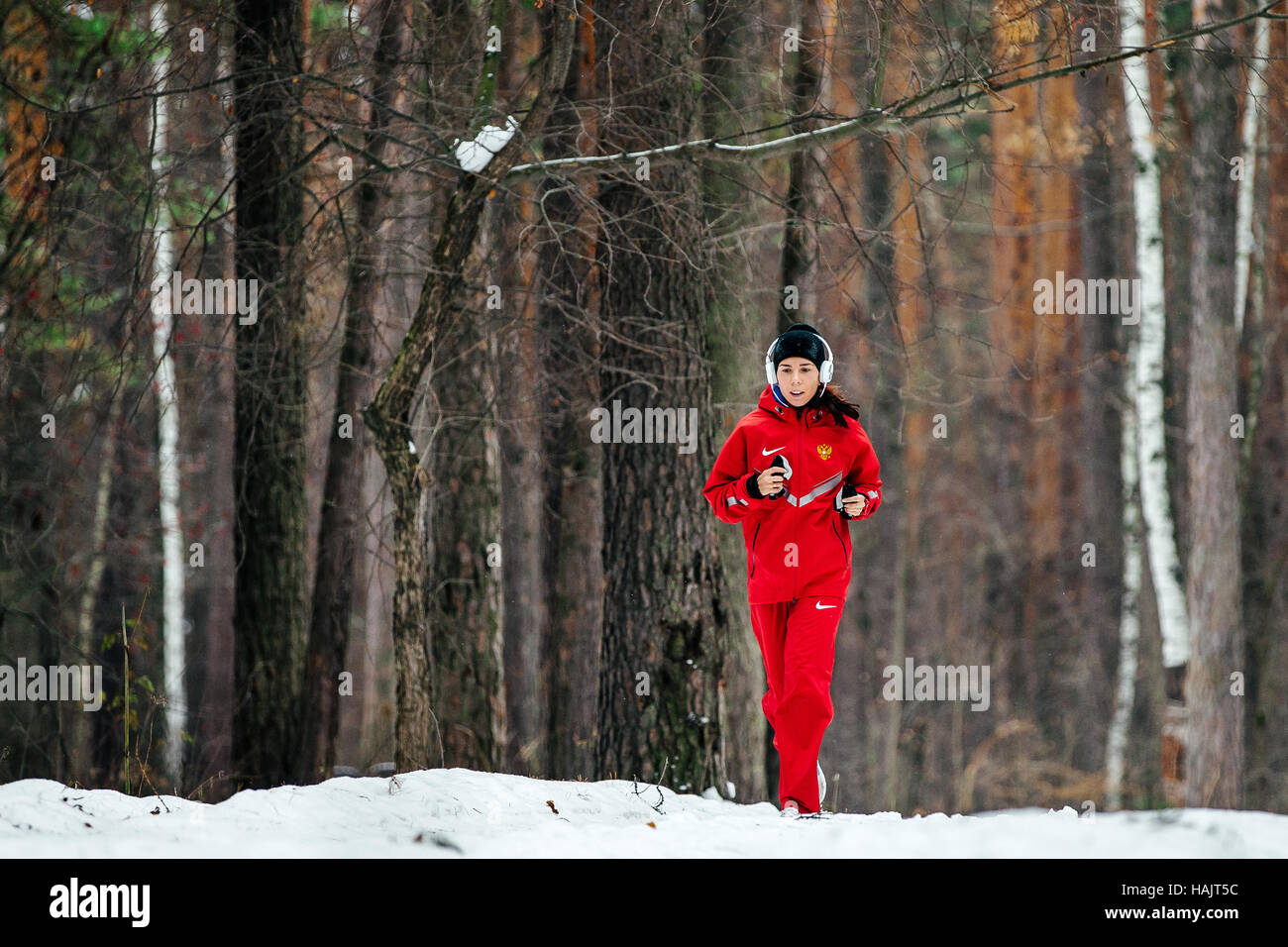 junges Mädchen im Kopfhörer verschneiten Kiefernwald während Winter Marathon laufen Stockfoto