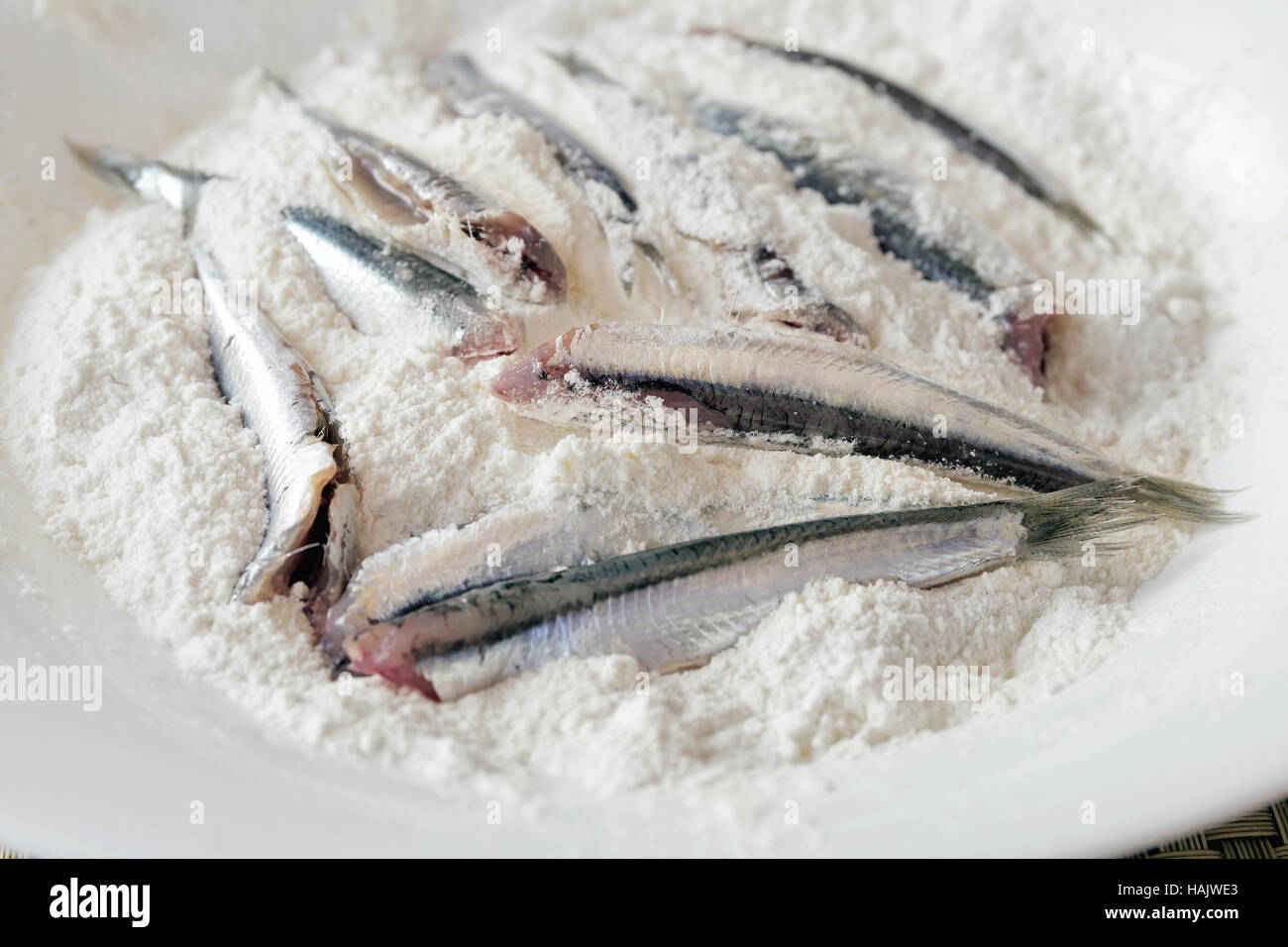 Panierte Sardellen, sauber und fertig gekocht werden. Sardellen in die Schüssel gefüllt mit weißem Mehl. In Öl braten. Stockfoto