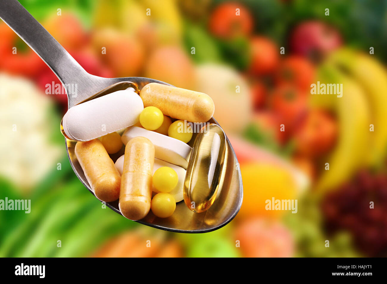 Löffel mit Nahrungsergänzungsmitteln auf Früchte Hintergrund Stockfoto