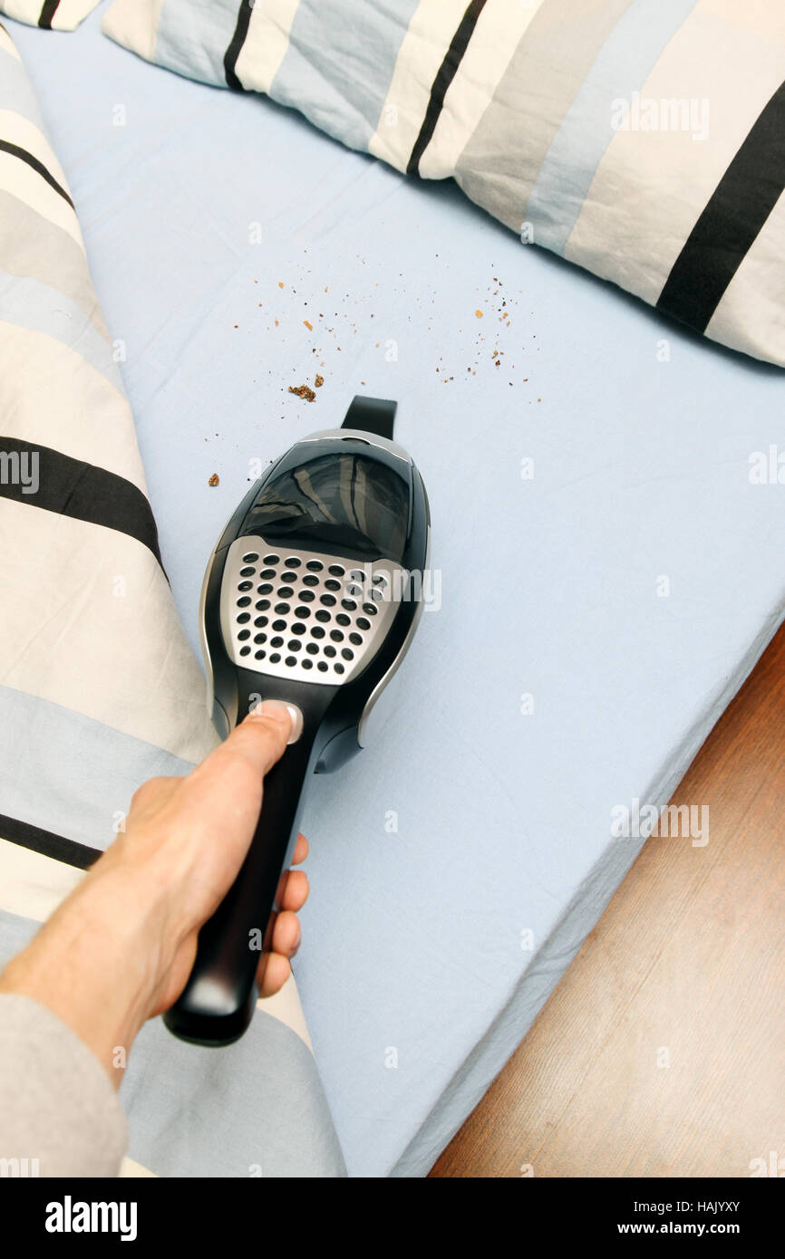 Krümel aus dem Bett mit Staubsauger reinigen Stockfoto