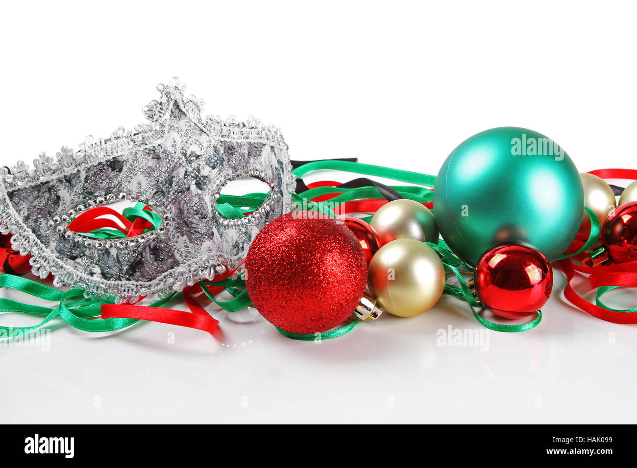 Weihnachtskugeln und Karnevalsmaske isoliert auf weiss Stockfoto