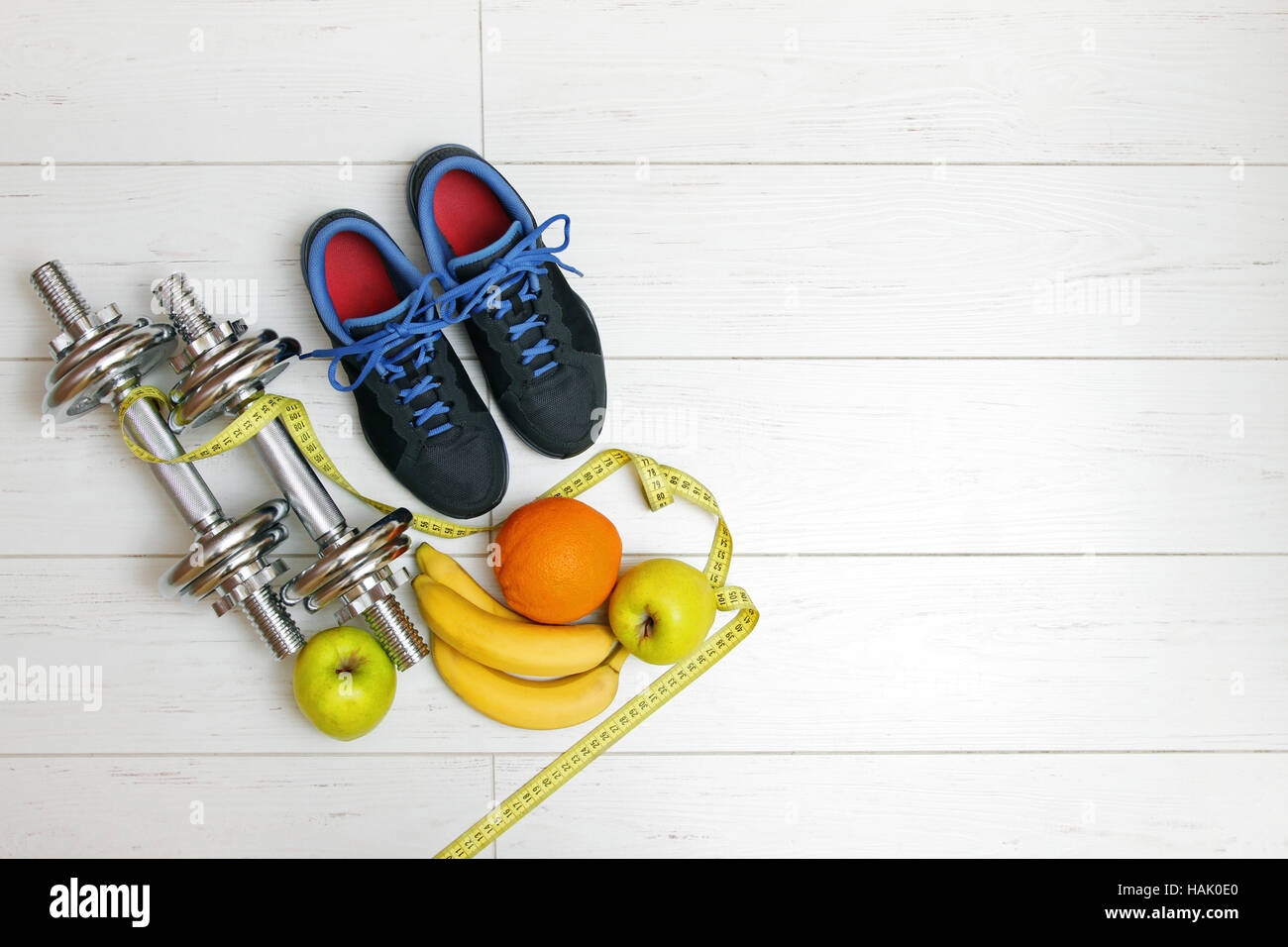 Fitnessgeräte und Früchte auf weißen hölzernen Dielenboden Stockfoto