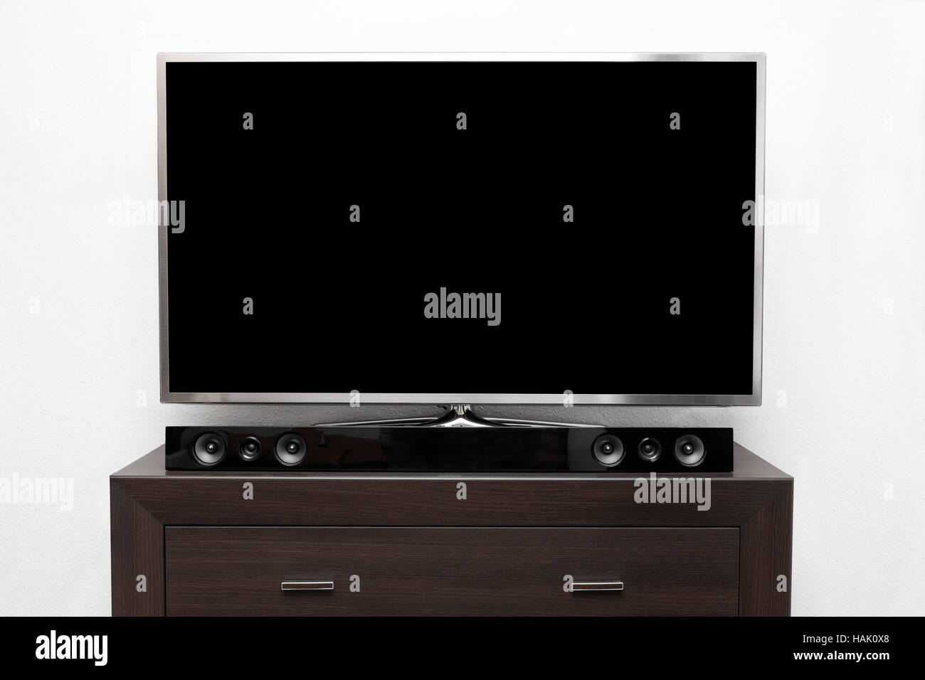 großer Fernseher mit leeren Bildschirm auf braune Kommode an weißer Wand Stockfoto