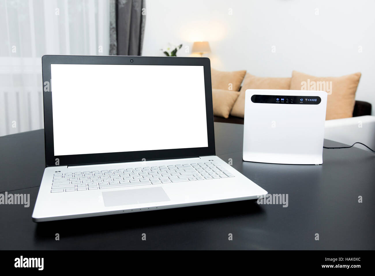 Laptop mit leeren Bildschirm und wireless Internet-Router auf dem Tisch Stockfoto