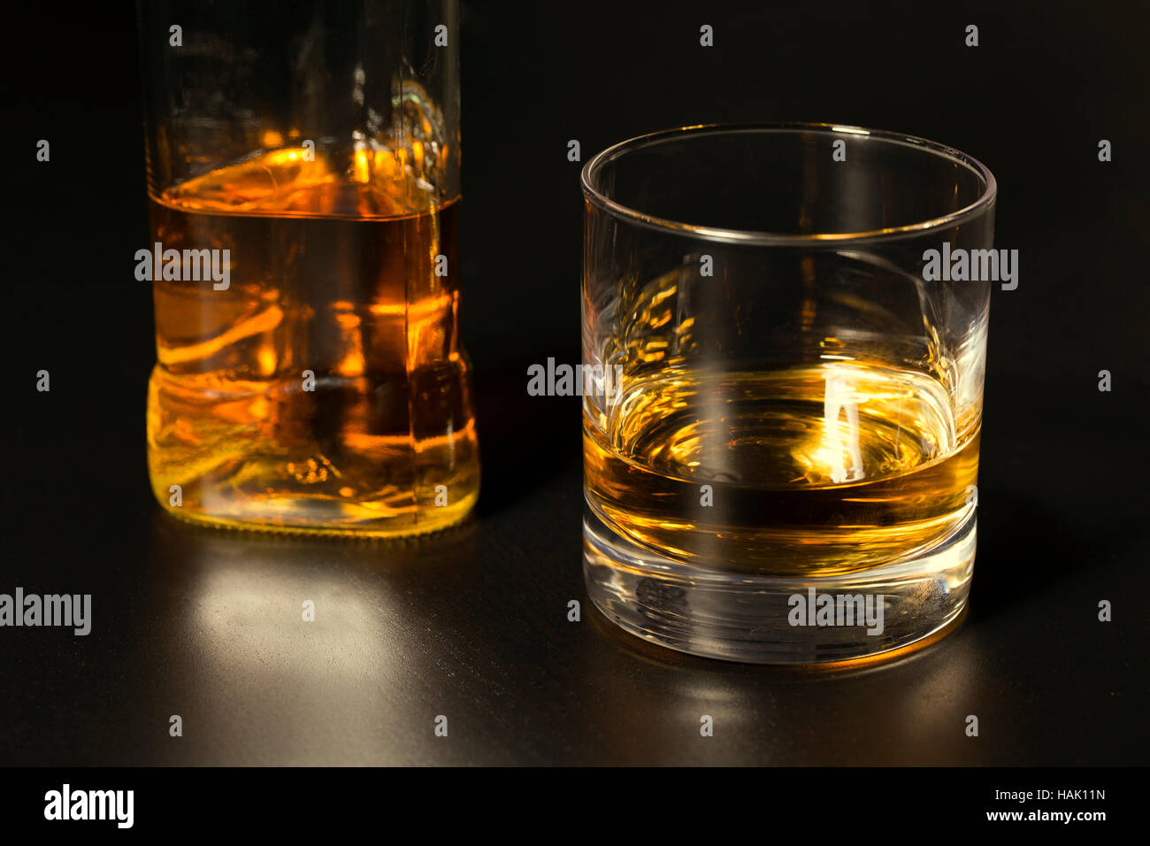 ein Glas Whiskey und Flasche auf dunklen Tisch Stockfoto