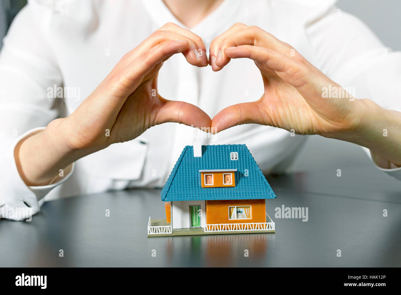 Nächstenliebe, Immobilien und Familie Wohnkonzept - menschliche hand in Herzform über kleine Plastikhaus Stockfoto