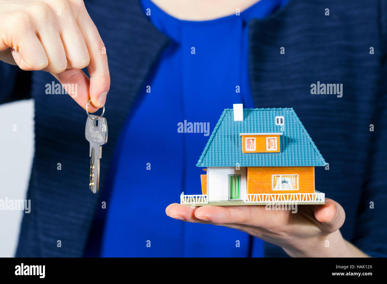 Immobilienmakler mit Schlüssel und Haus-Modell auf der Seite Stockfoto