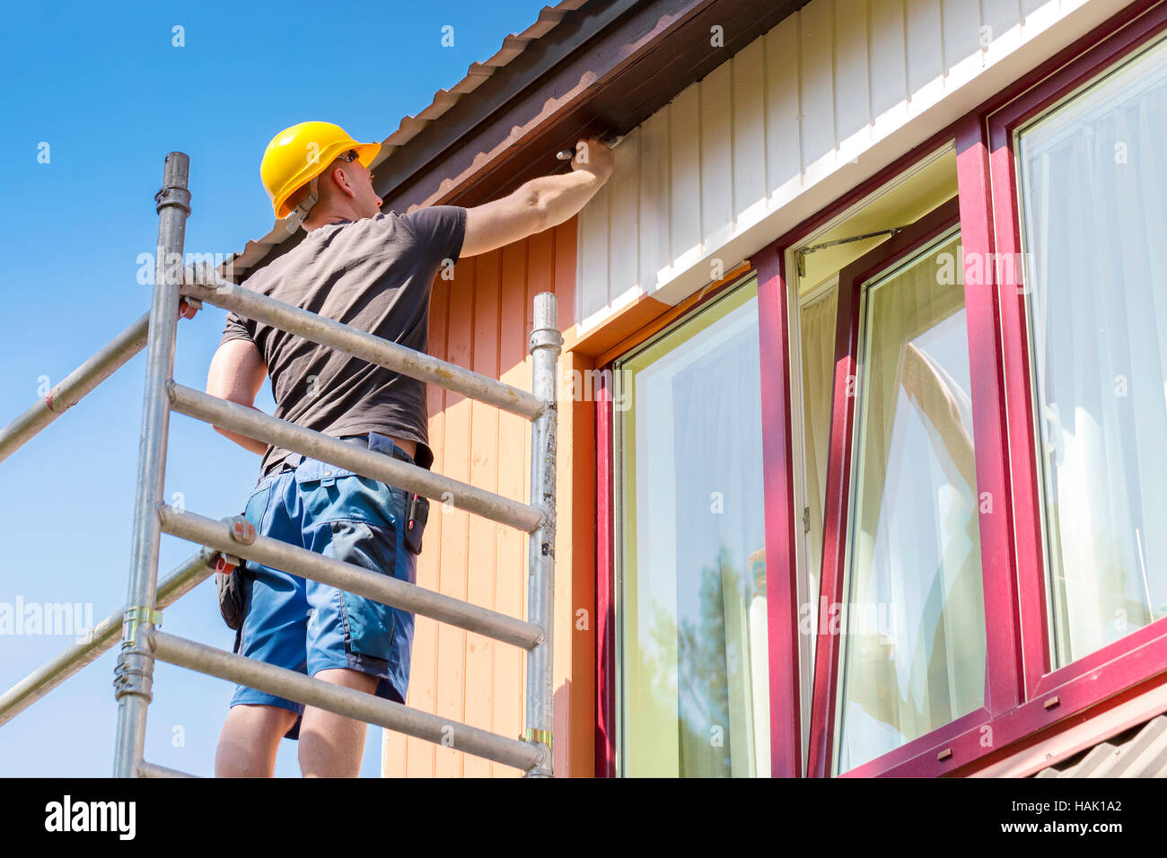 Bauarbeiter auf einem Gerüst Malerei Holzhaus Fassade Stockfoto