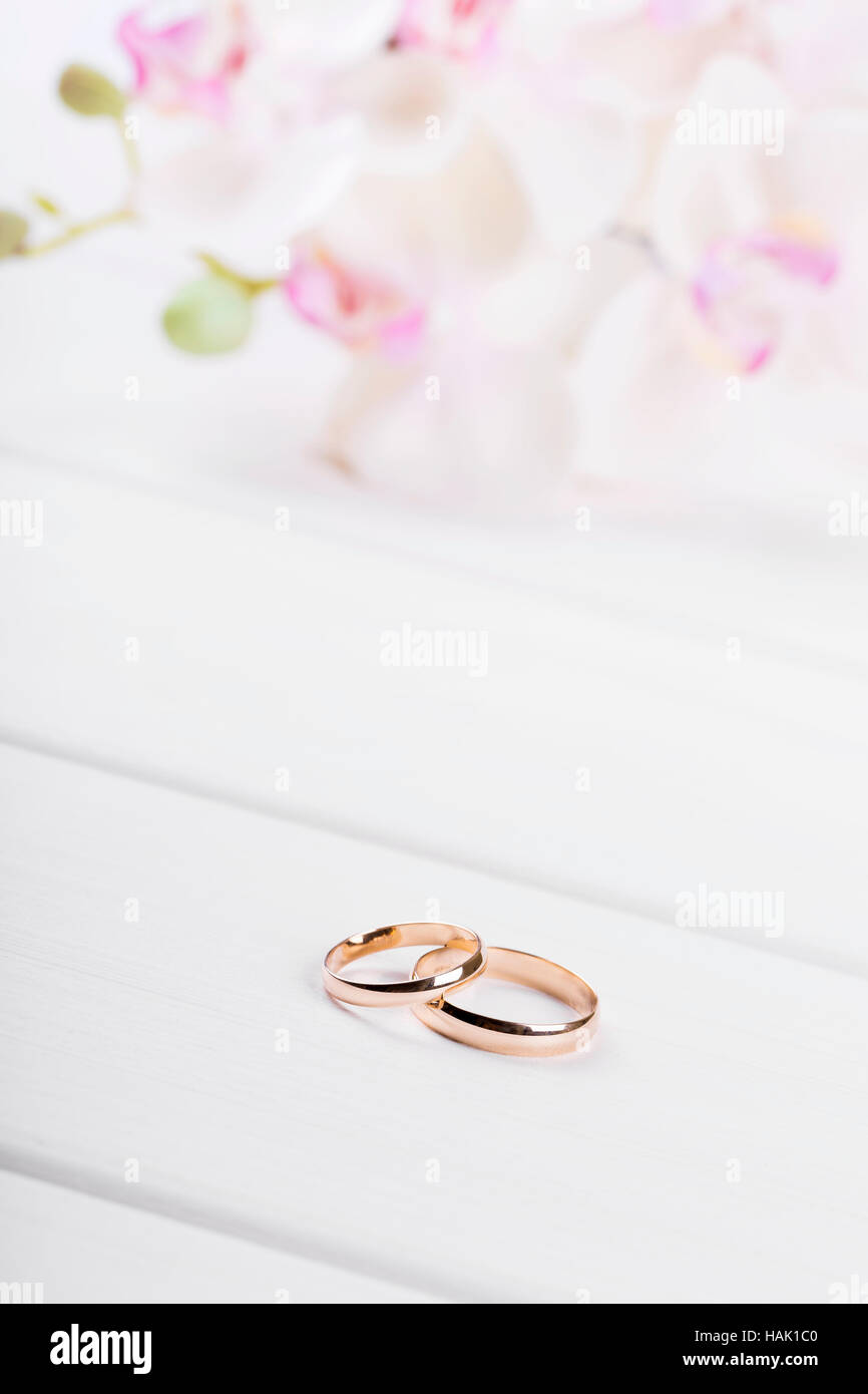 Goldene Hochzeit Ringe mit Blumen auf weißer Holztisch Stockfoto