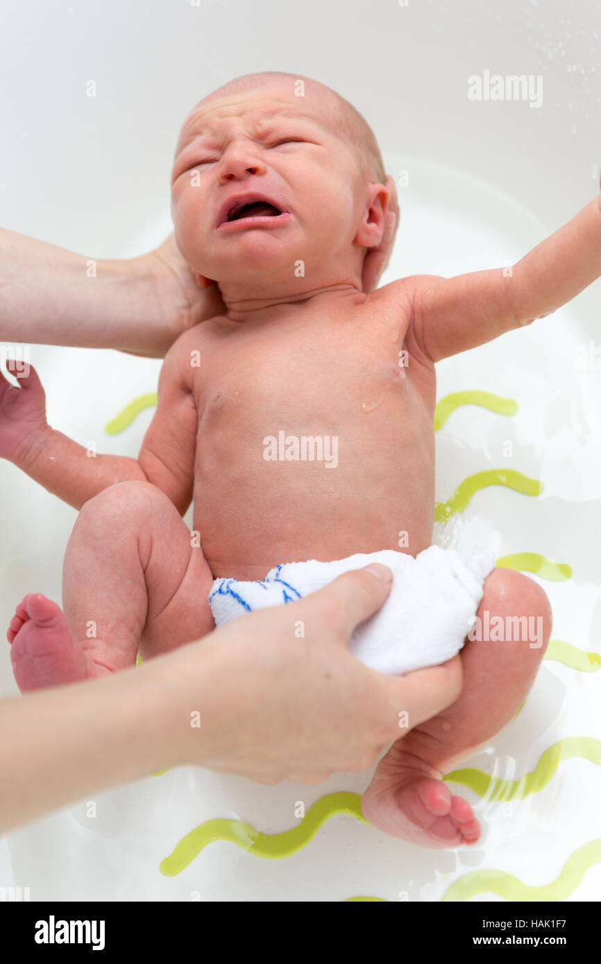 neugeborenes Baby Mädchen unter Bad mit Mütter Hilfe Stockfoto