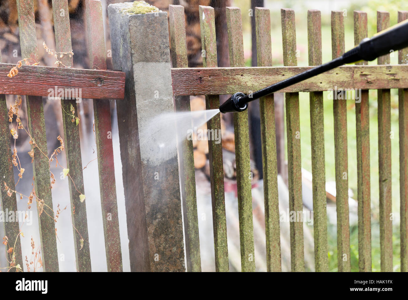 Reinigung schmutziger Gartenzaun Post mit Hochdruckreiniger Stockfoto