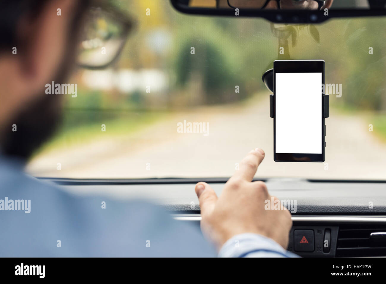 Mann zeigte auf leere Smartphone-Bildschirm in Auto Windschutzscheibe Halterung Stockfoto