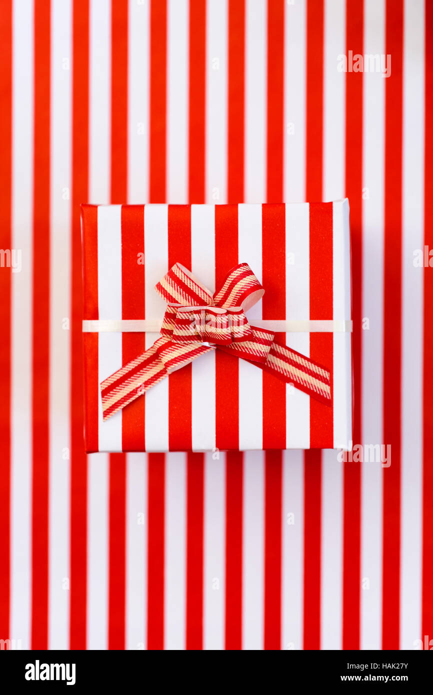 High-Angle Schuss ein elegantes Geschenk in einem rot-weiß gestreift-gemusterten Papier eingewickelt und gekrönt mit einer Schleife Rot und weiß gestreift gemustert, Stockfoto