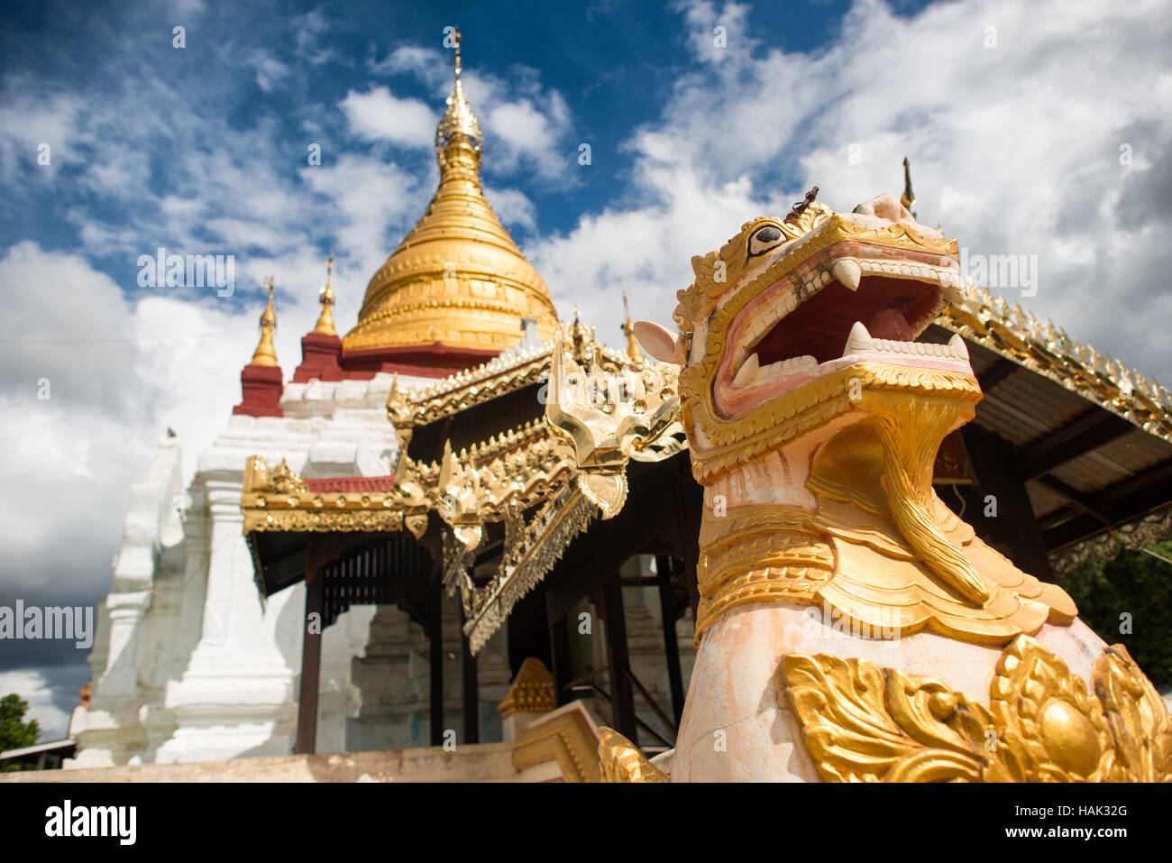 BAGAN, Myanmar – Eine goldene Löwenstatue bewacht den Eingang zu einer vergoldeten Stupa in der Gegend von Bagan, Myanmar. Die kunstvoll verzierte buddhistische Struktur strahlt im Sonnenlicht und zeigt die reichen künstlerischen Traditionen der birmanischen Tempelarchitektur. Stockfoto