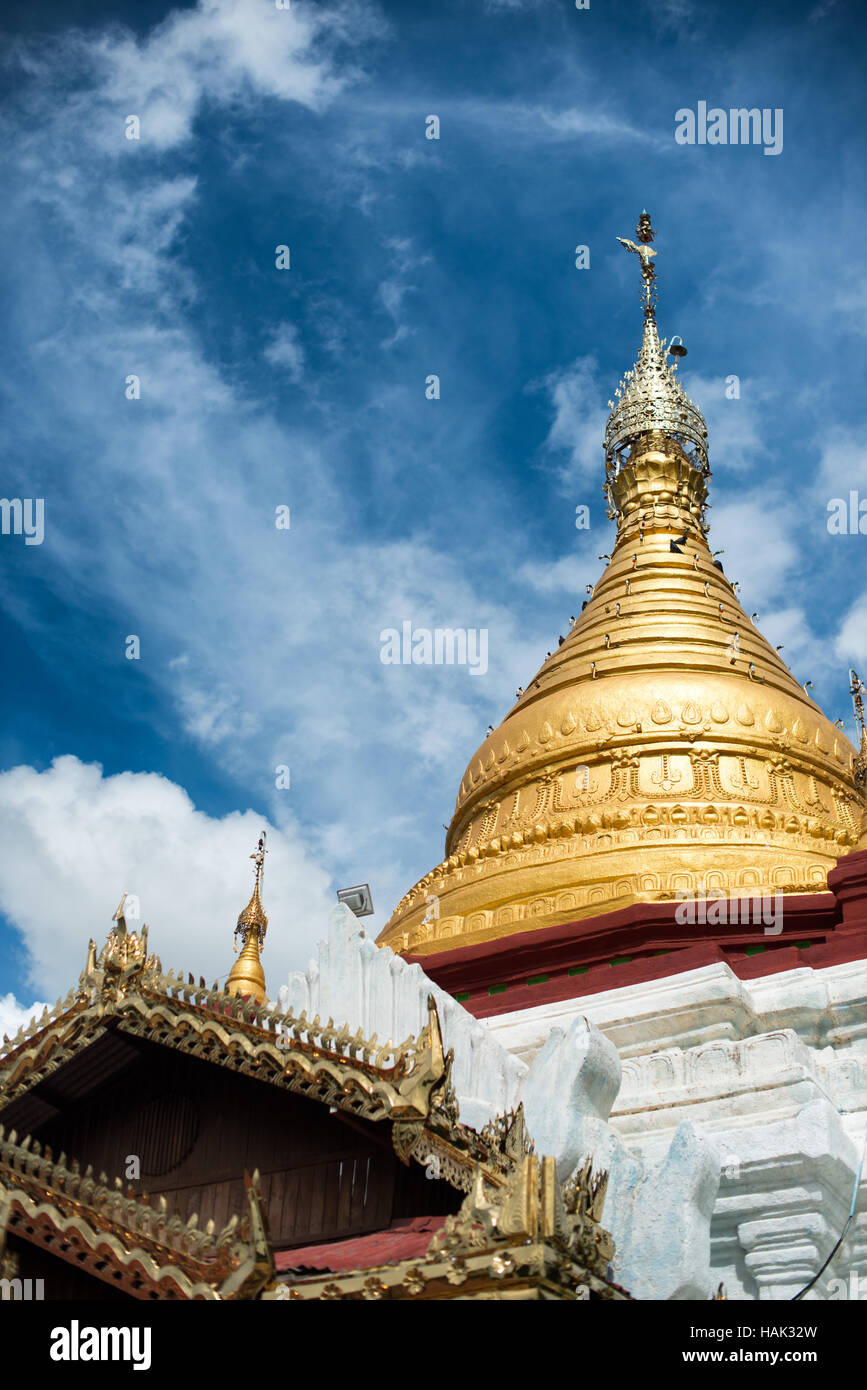 Shwe Kyaung U Tempel Stupa Bagan Myanmar // BAGAN, Myanmar – die kunstvolle Dachlinie und die goldene Stupa des Shwe Kyaung U Tempels zeigen traditionelle burmesische buddhistische Architektur in der archäologischen Zone Bagan. Dieser Tempel aus dem 18. Jahrhundert, der als Denkmal 2007 in Pierre Pichards architektonischem Inventar dokumentiert ist, befindet sich in einem Klostergelände nordöstlich von Pagan in der Nähe des Dorfes Taungbi. Der Tempel verfügt über eine unverwechselbare Kombination aus traditionellem Mauerwerk mit einem Holzpavillon auf der Westseite, was seine aktive Nutzung durch die ansässige Klostergemeinschaft widerspiegelt. Die Struktur“ Stockfoto