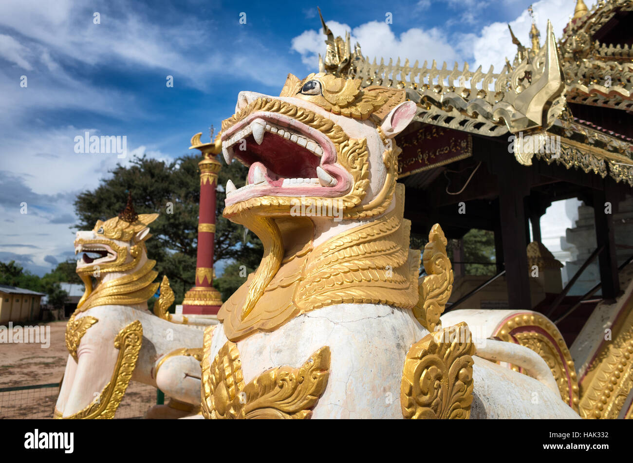 BAGAN, Myanmar – Eine goldene Löwenstatue bewacht den Eingang zu einer vergoldeten Stupa in der Gegend von Bagan, Myanmar. Die kunstvoll verzierte buddhistische Struktur strahlt im Sonnenlicht und zeigt die reichen künstlerischen Traditionen der birmanischen Tempelarchitektur. Stockfoto