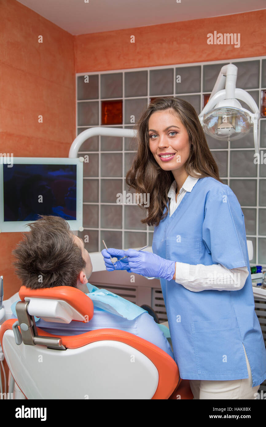 Junger Mann mit medizinischer Checkup in der Zahnarztpraxis durch die junge Ärztin Stockfoto