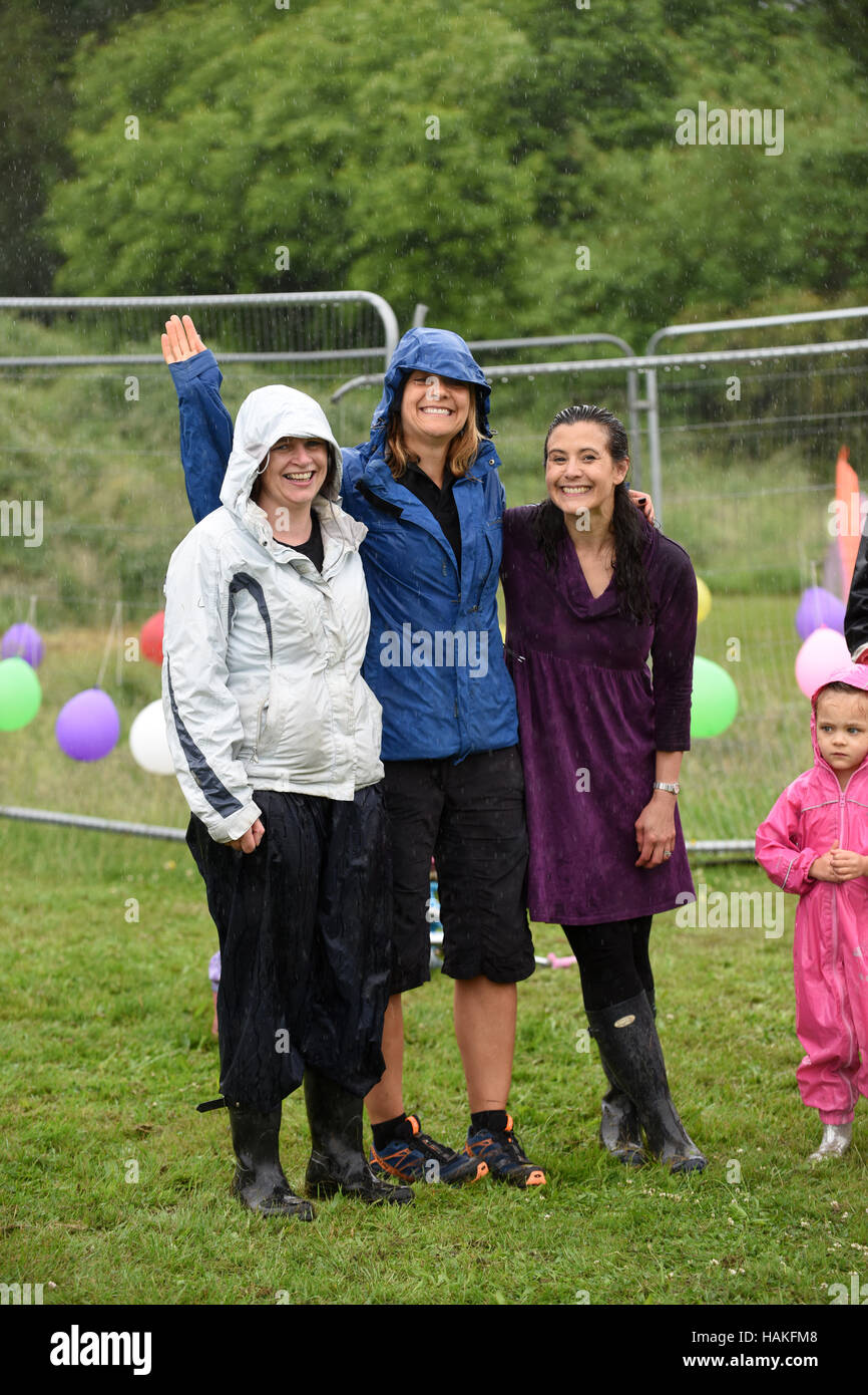 Lächelnd im Regen! Frauen und Kinder Spaß trotz Regenwetter an einem englischen Sommerfest Uk Stockfoto