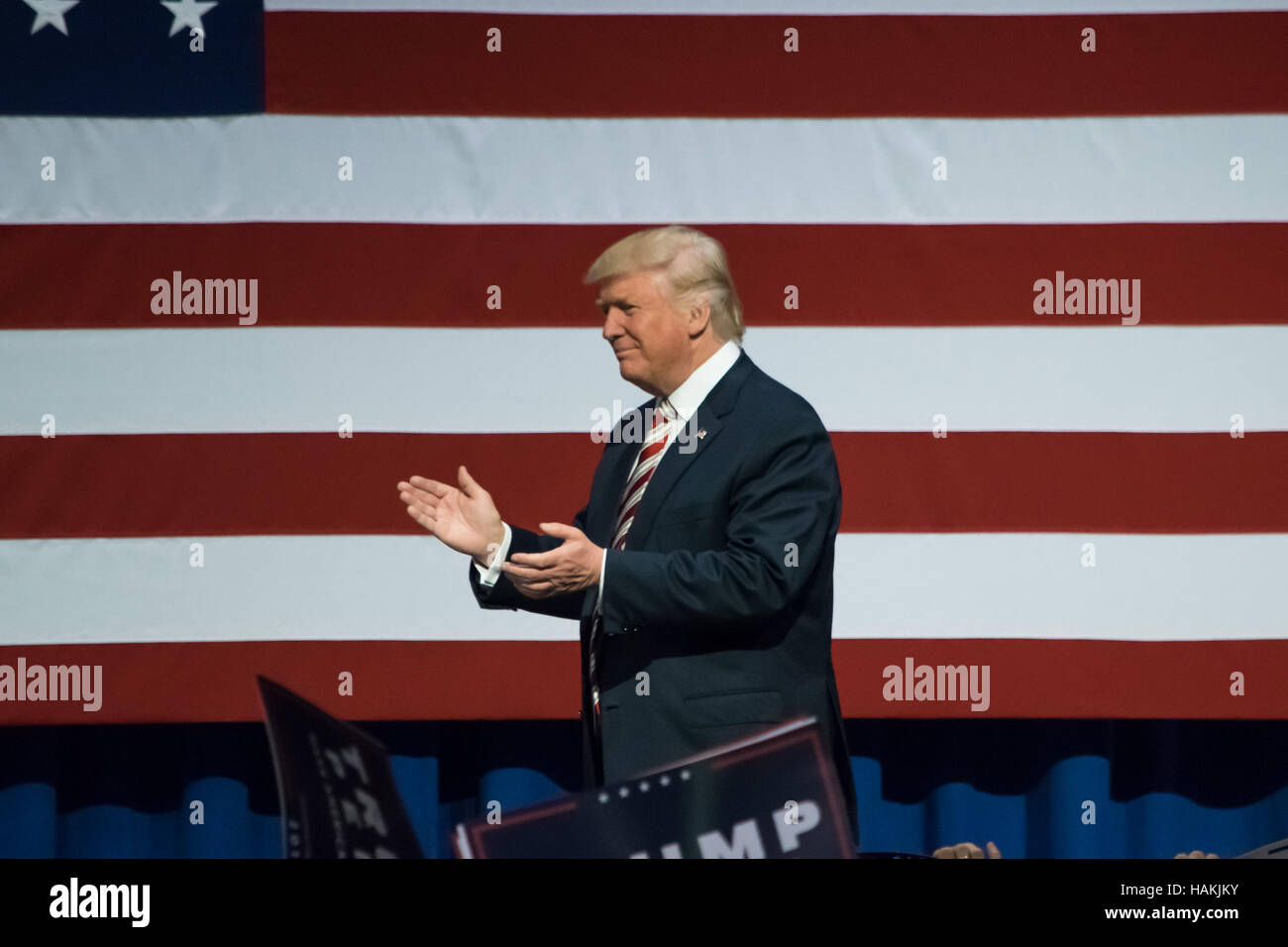 Republikanische Präsidentschafts Kandidat Donald Trump zu Fuß auf der Bühne Beifall der Menge in der Nähe der amerikanischen Flagge. Stockfoto