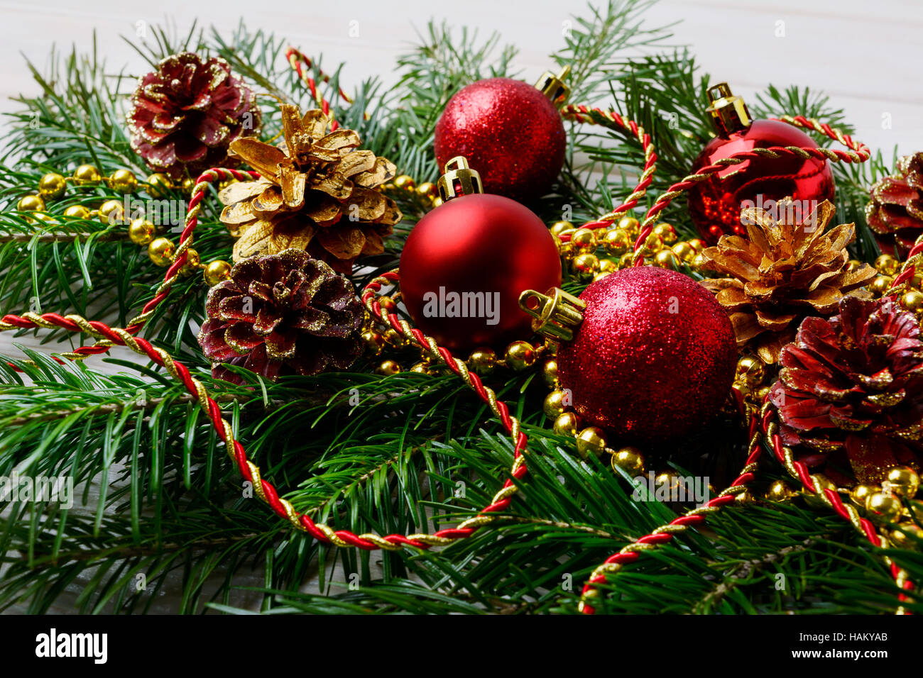 Weihnachtsgirlande mit roten Verzierungen und goldenen Tannenzapfen. Weihnachten-Tafelaufsatz mit goldenen Dekor. Stockfoto