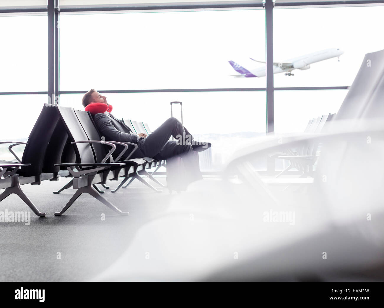 Geschäftsmann ruht mit Nackenkissen im Abflugbereich des Flughafen Stockfoto