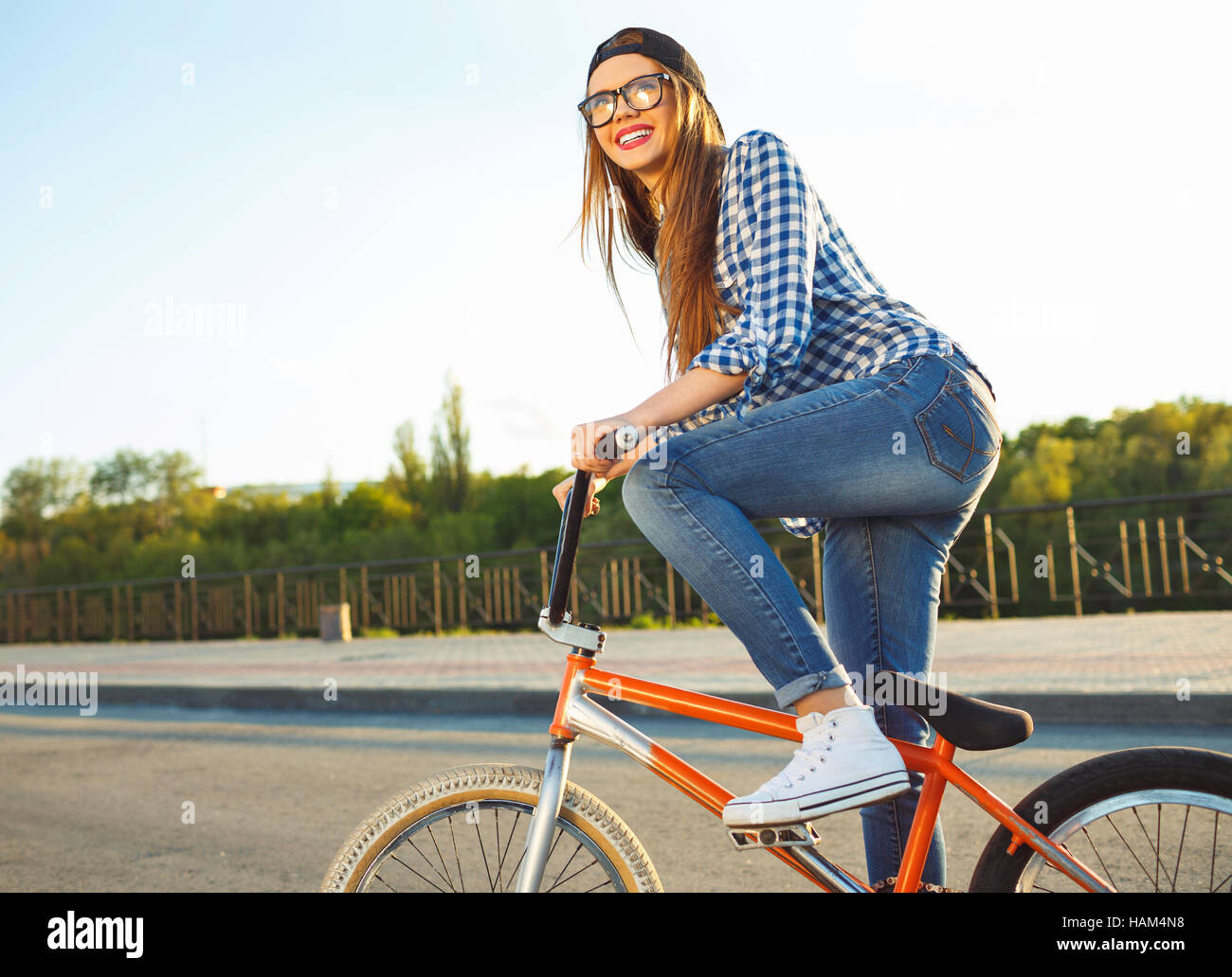 Schöne junge Frau mit Hut mit dem Fahrrad auf Stadt Hintergrund im Sonnenlicht im Freien. Aktive Menschen Stockfoto