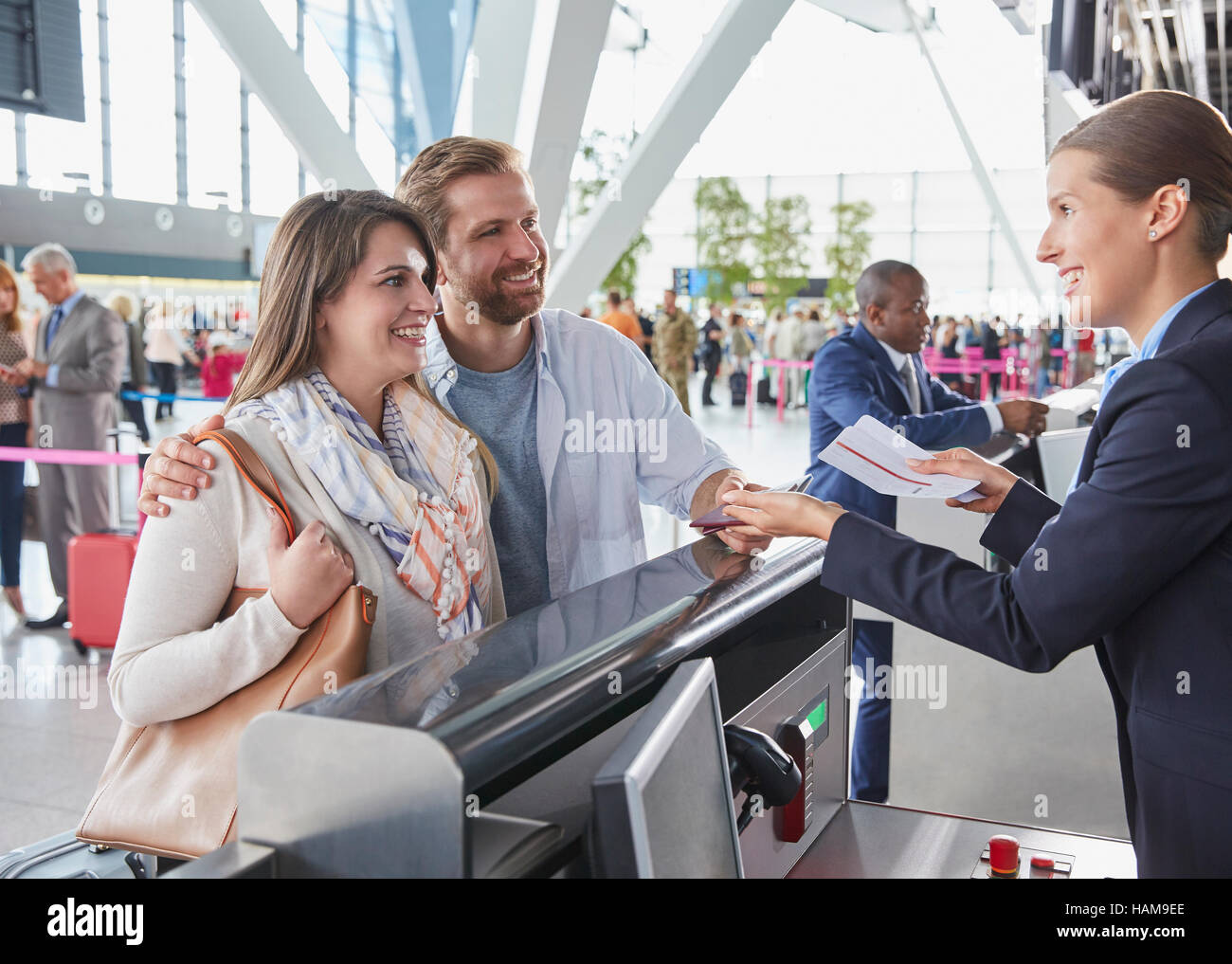 Mitarbeiter des Kundendienstes helfen paar am Flughafen-Check-in-Schalter Stockfoto