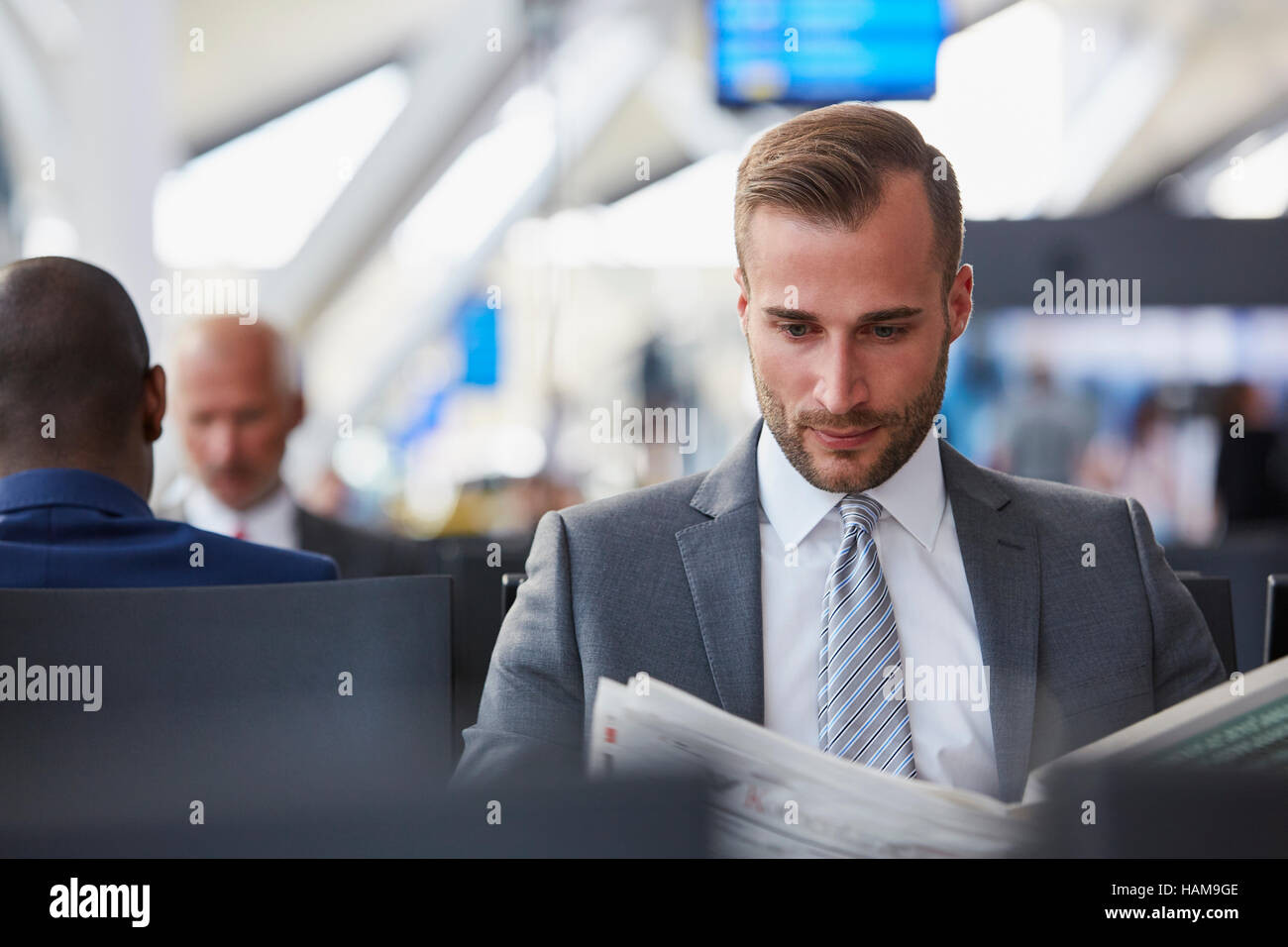 Geschäftsmann Zeitunglesen im Abflugbereich des Flughafen Stockfoto