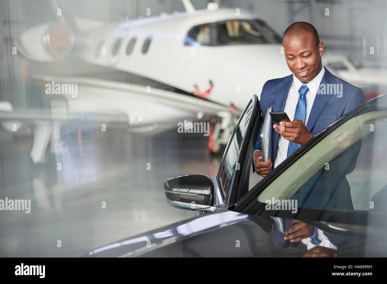 Geschäftsmann mit Handy ins Auto in der Nähe von Geschäftsreiseflugzeugen im hangar Stockfoto