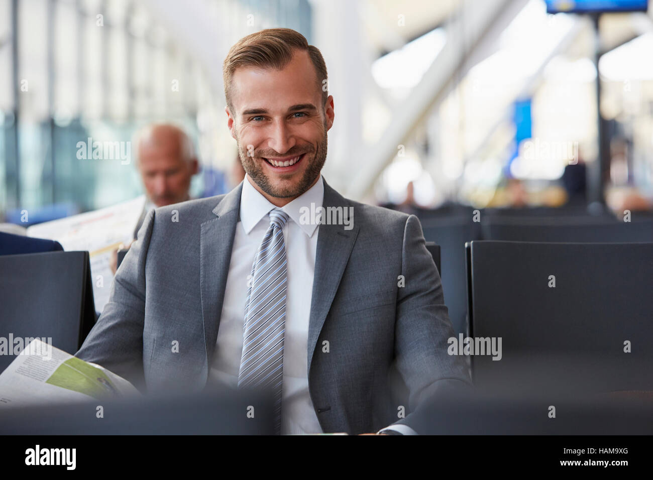 Porträt, Lächeln Geschäftsmann lesen Zeitung im Abflugbereich des Flughafen Stockfoto