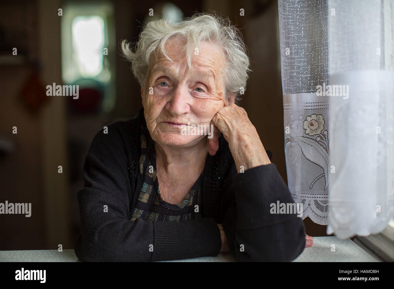 Arme alte Frau in ihrem Haus, Blick in die Kamera. Stockfoto