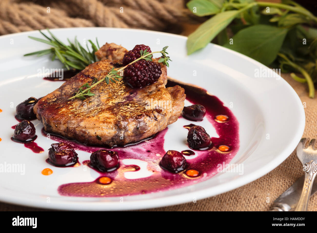 Konzept: Speisekarten, gesundes Essen, hausgemachte, Feinschmecker, Völlerei. Schweinesteak auf den Knochen mit Kirsch-Ingwer-Sauce mit Zutaten auf chaotisch sa Stockfoto