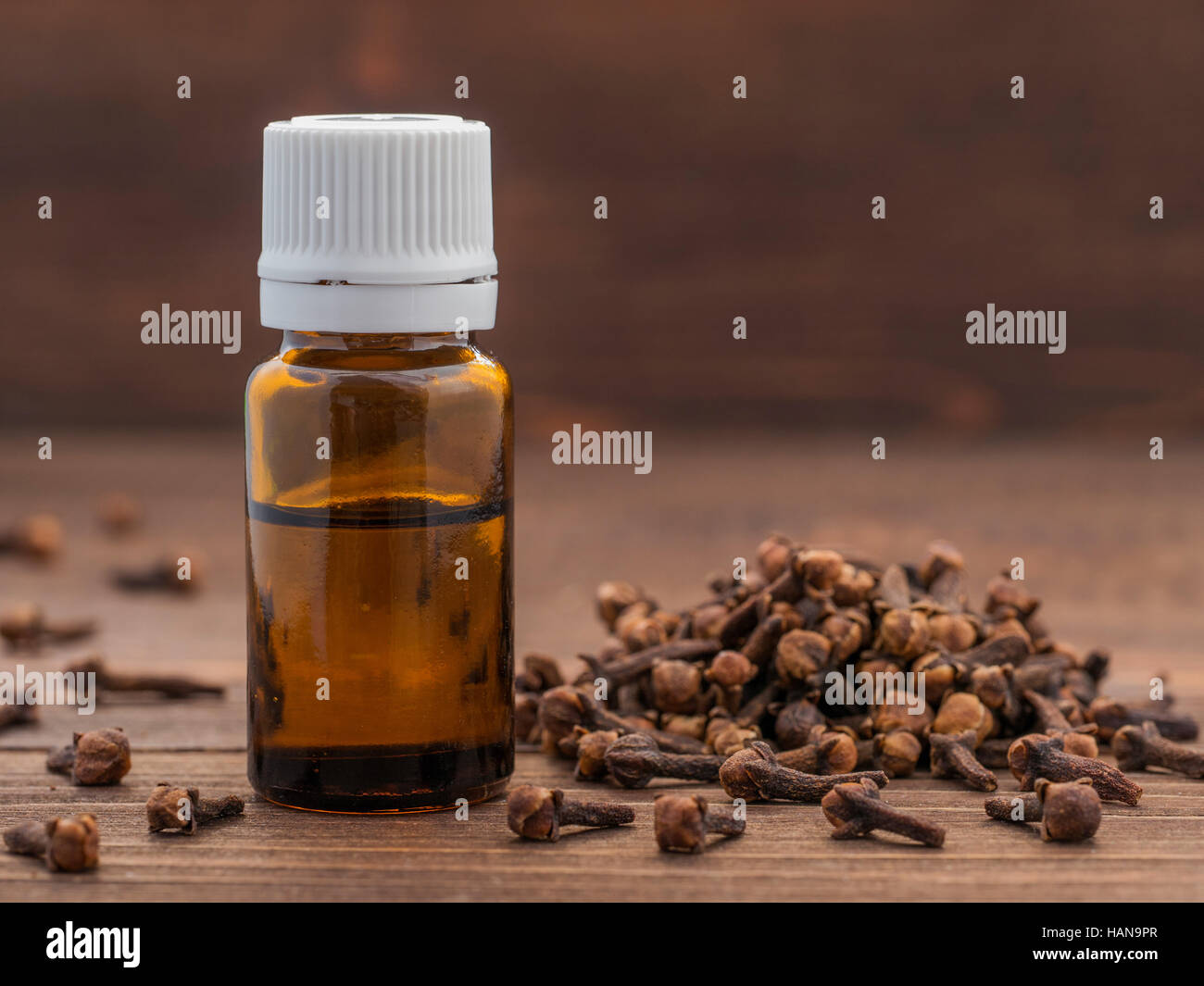 Gewürz Nelke ätherisches Öl in dunklem Glas Flasche Anddry Nelken auf dunklem Holz mit Textfreiraum Stockfoto